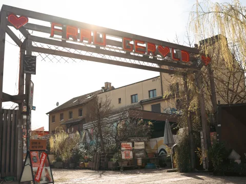 Un grand portail en bois marque l’entrée sur un site hétérogène et artistique. L’inscription «Frau Gerold» figure en rouge sur l’arc du portail.