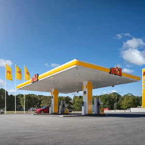 St1-station i strålande sol. Himlen är blå med några vita slöjmoln. Tre gula St1-flaggor vajar i vinden.