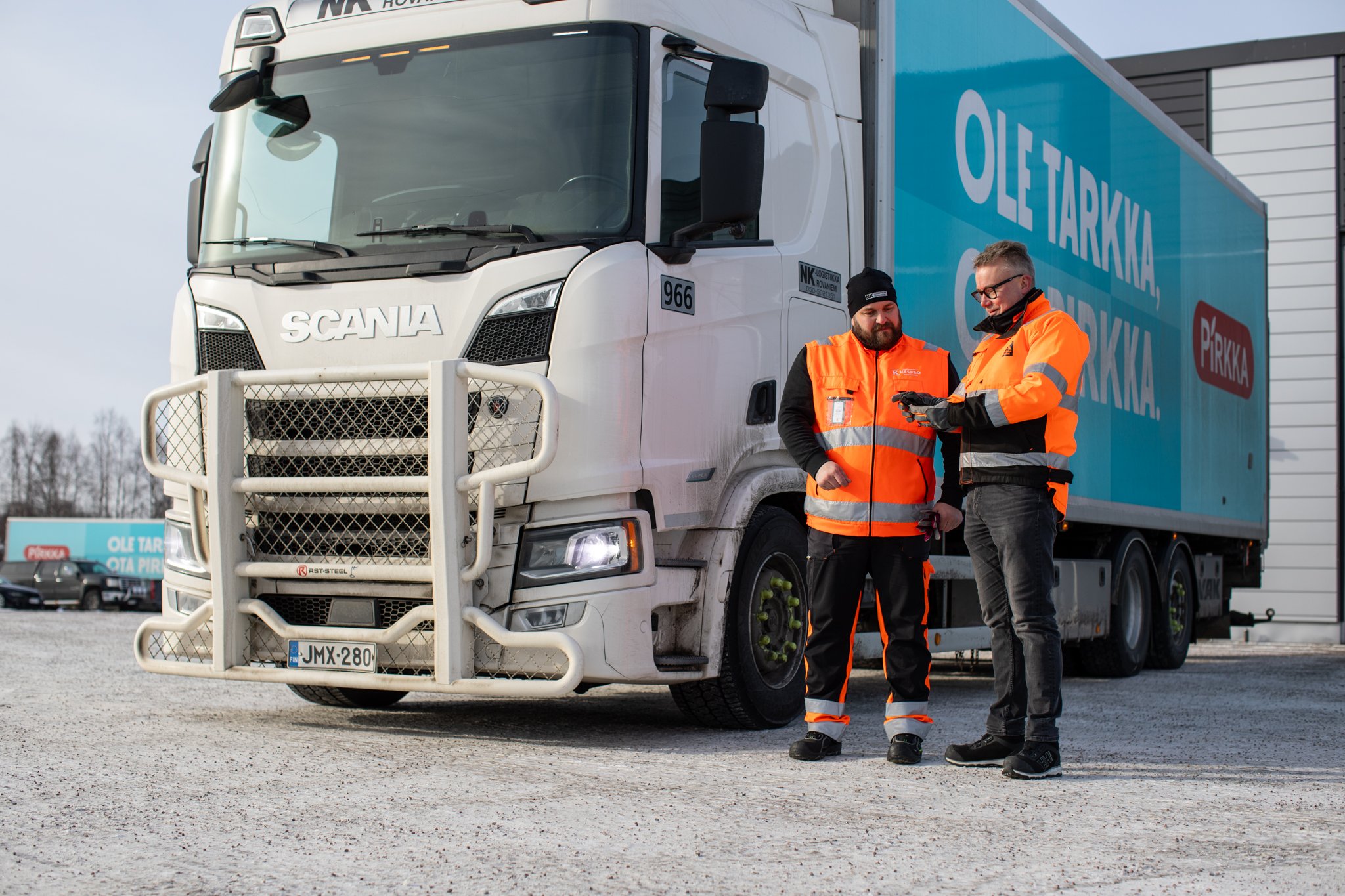 Kaksi henkilö seisoo rekan vieressä.