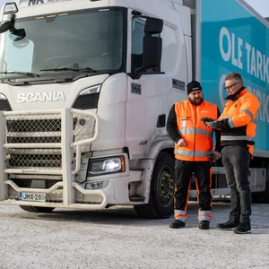 Kaksi henkilö seisoo rekan vieressä.