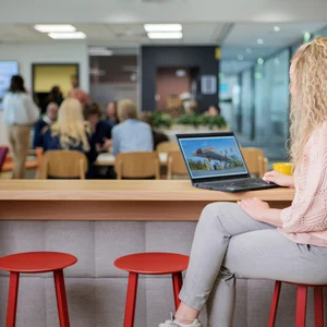 Henkilö istuu pöydän ääressä läppäri auki.