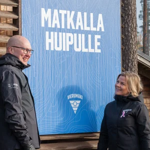 Kaksi miestä istuu laavulla nuotion äärellä.