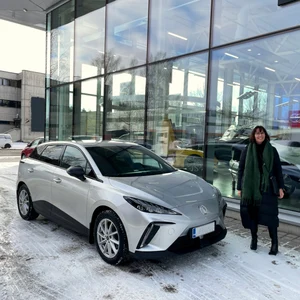 Kilpailun voittaja Minna ja sähköauto MG 4 Luxury autokaupan pihassa