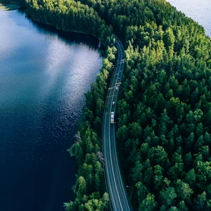 Väg kantad av träd med en sjö på vänster sida av vägen