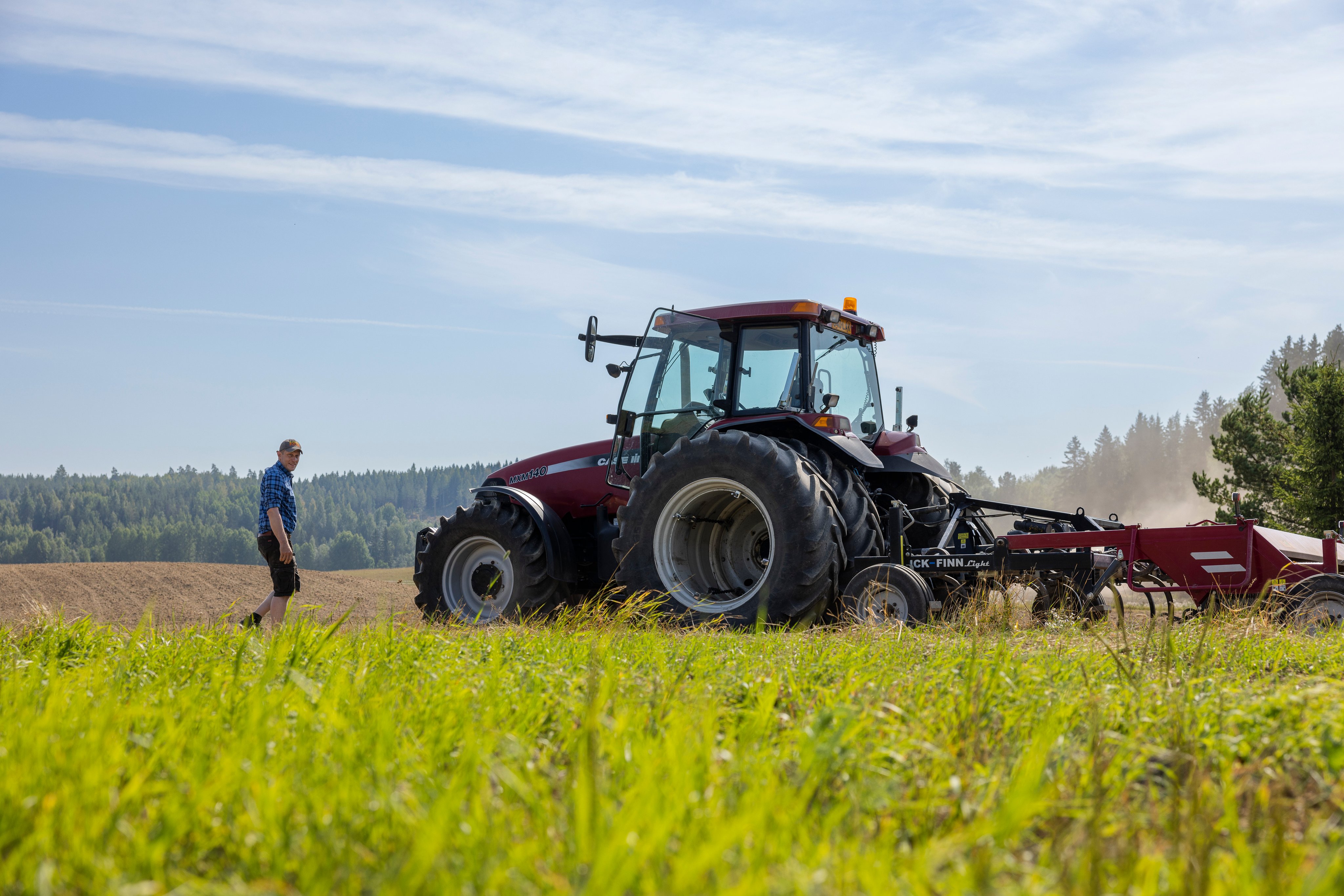 A man walking to his tractor on a green field.