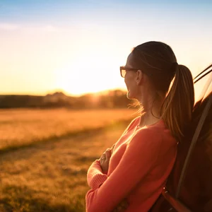 St1 Kvinna lutar sig mot bil och tittar på solnedgången
