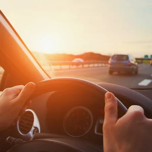 Person håller i ratten med två händer. Kör på motorväg.
