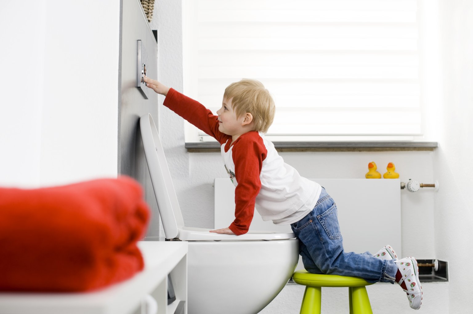 Kind drückt die Spülung der Toilette
