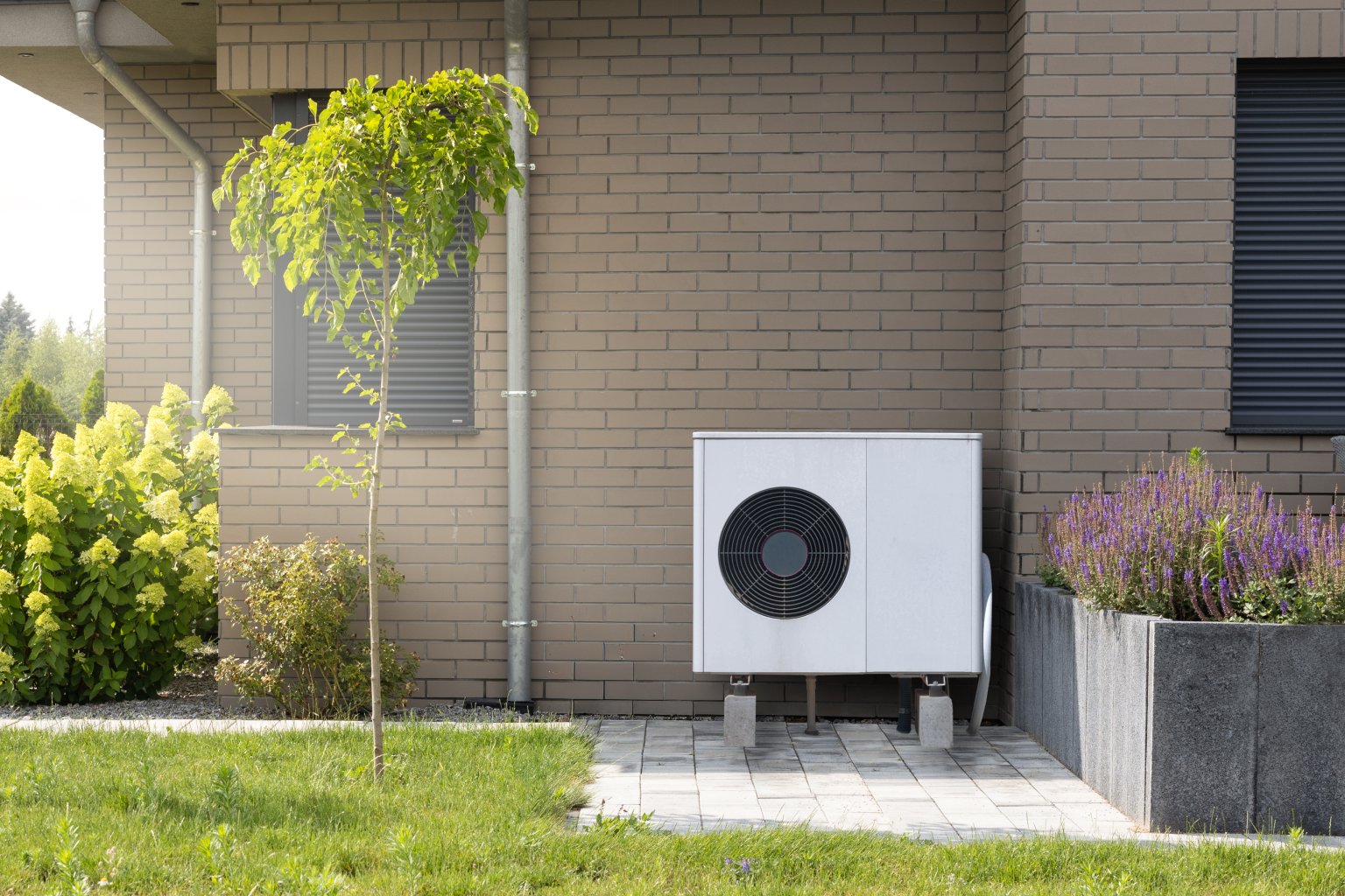 Eine Wärmepumpe steht vor einem Haus. © iStock.com/maxshot