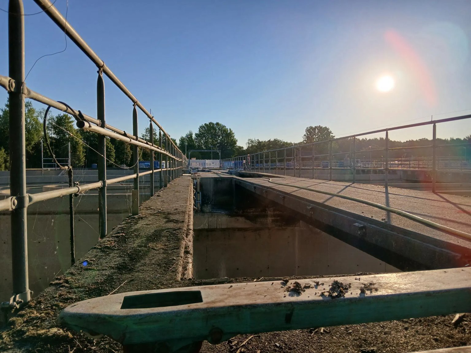 Blick auf eine Betonkonstruktion mit Metallgeländer und geparktem Fahrzeug bei Sonnenaufgang