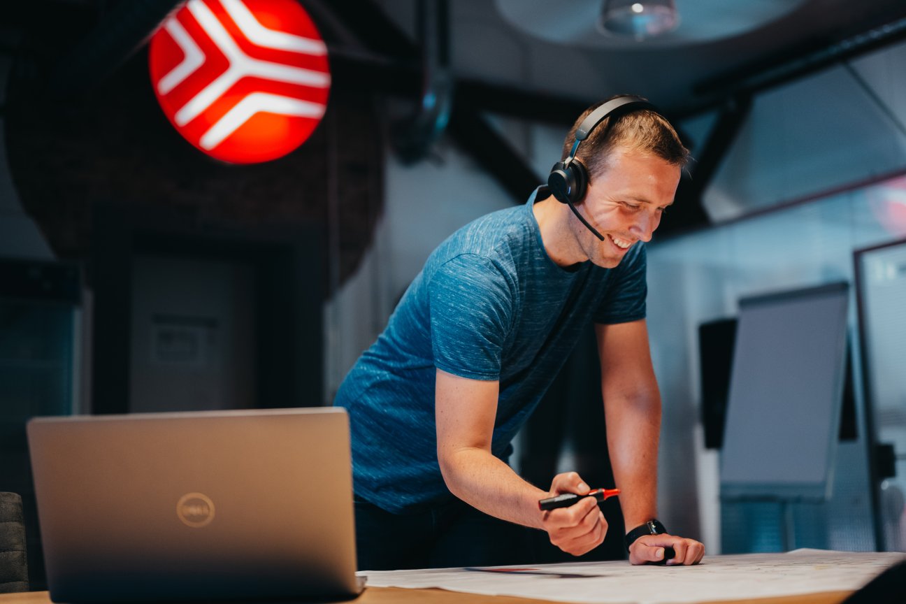 Ein Mann mit einem Headset, der auf einem Tisch arbeitet und etwas hält.