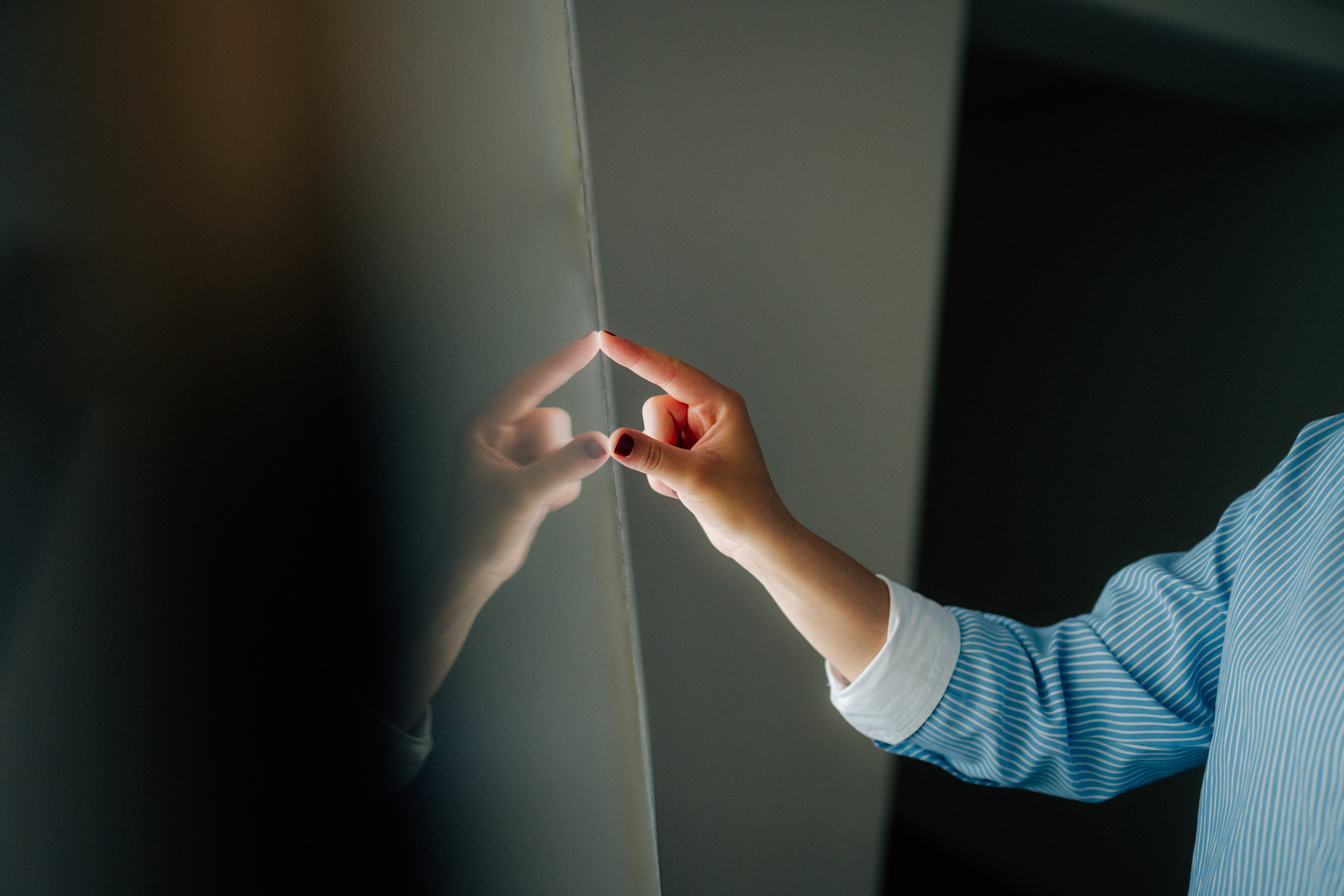 Eine Person berührt eine glatte, dunkle Wand mit ihrem Finger.