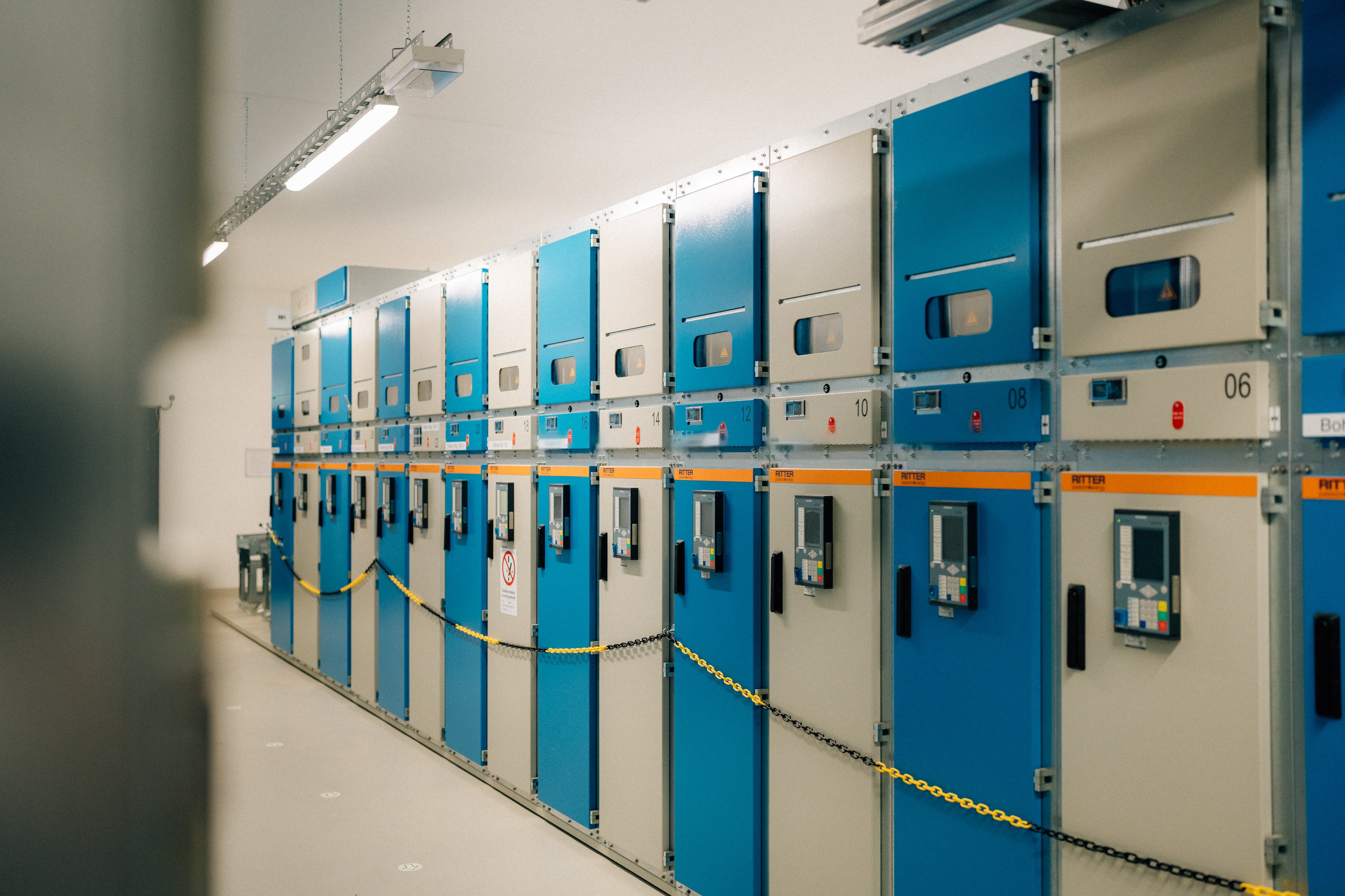 Reih industrieller Schaltschränke mit blauen Türen in einem Raum.
