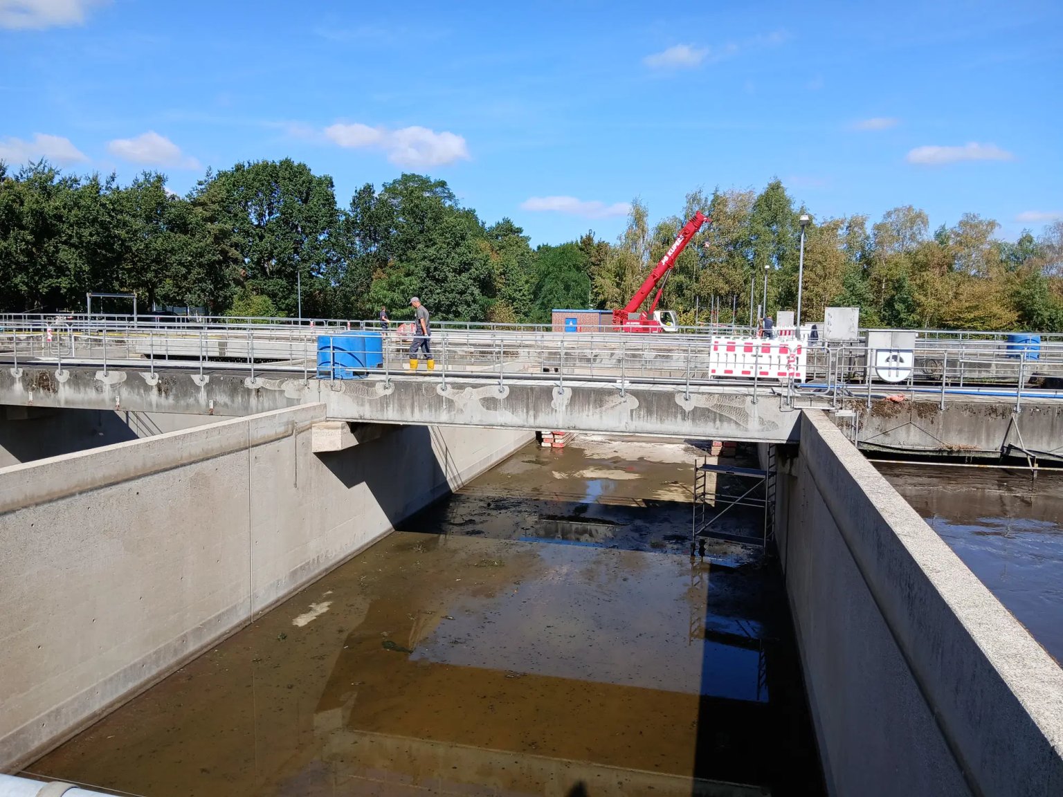 Brücke mit Wasserablauf und Bauarbeiten, eine Person steht oben.