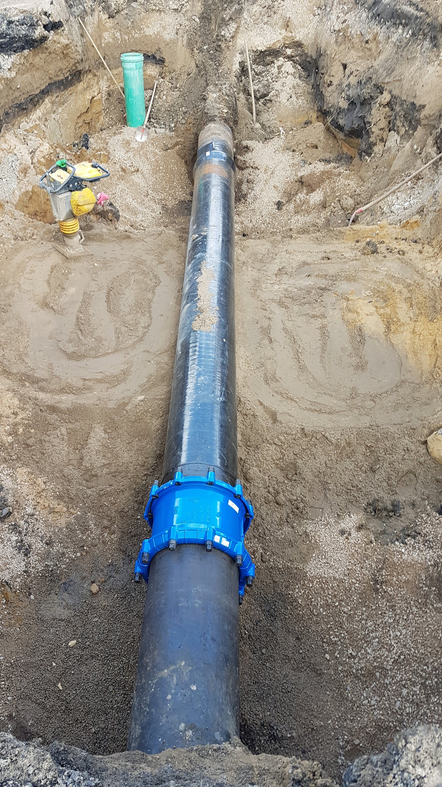 im Baustellengraben sind man den ausgewechselten Rohrabschnitt