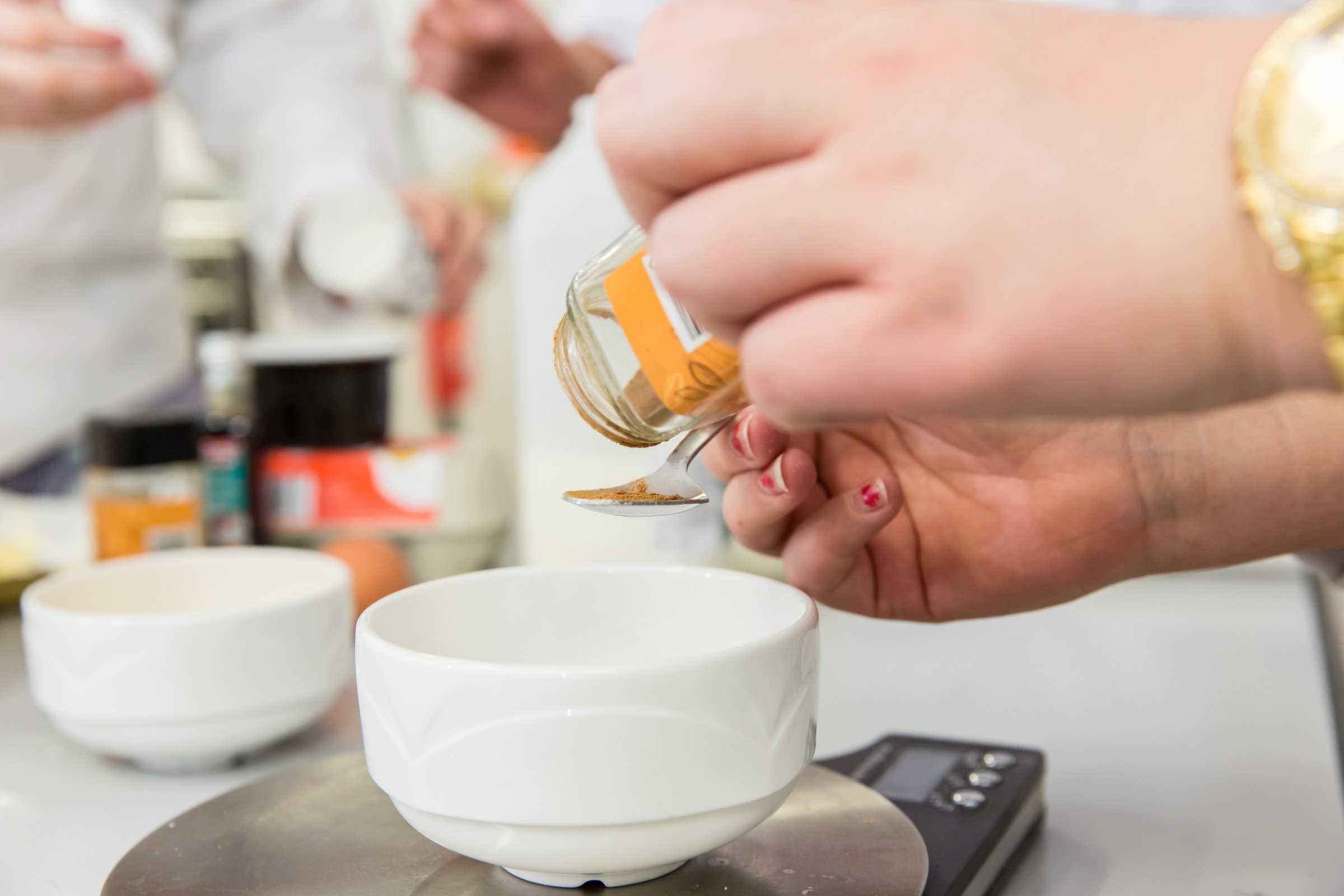 A student's hand using spice to add to a dish