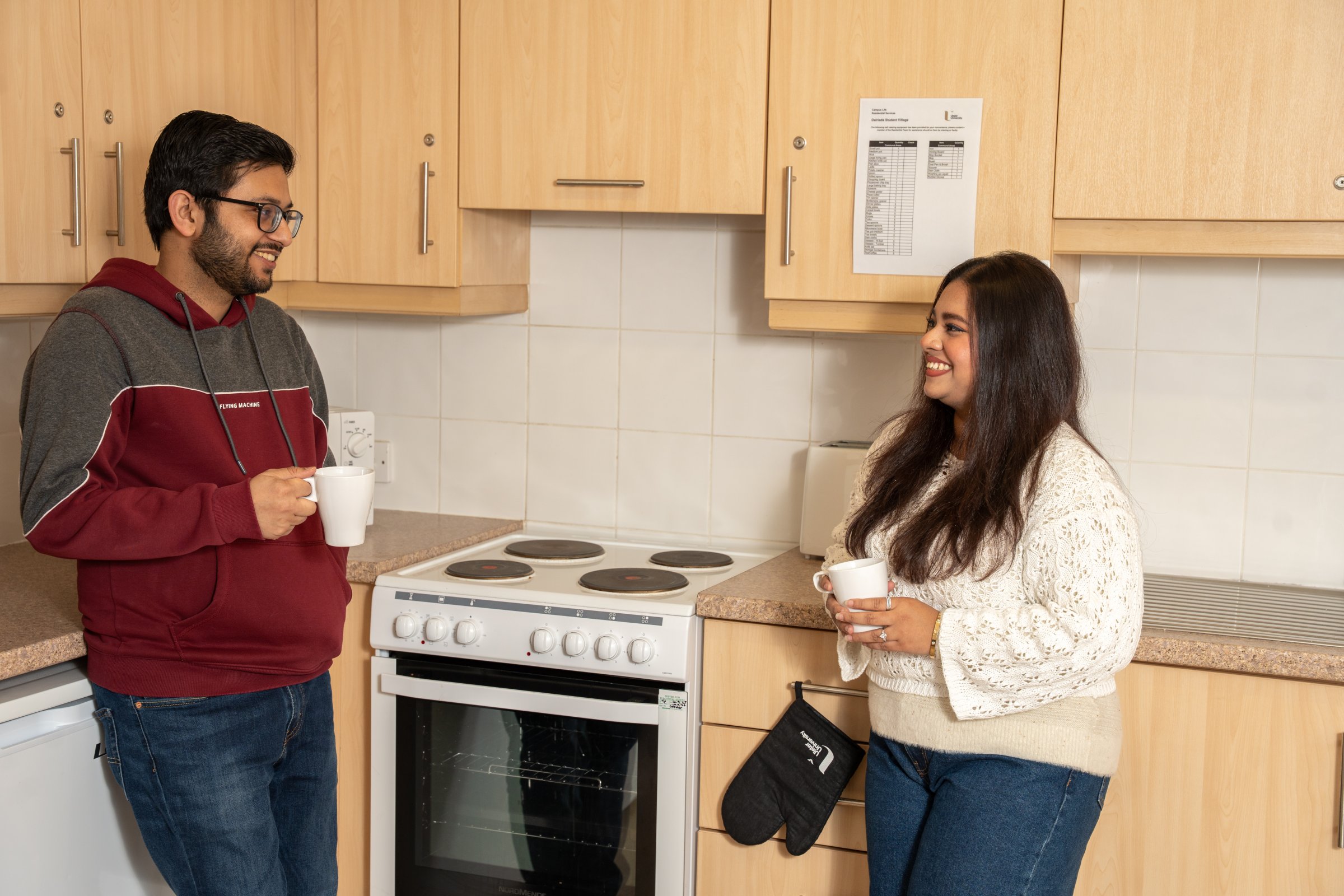Two students in accommodation in the kitchen having a cuppa