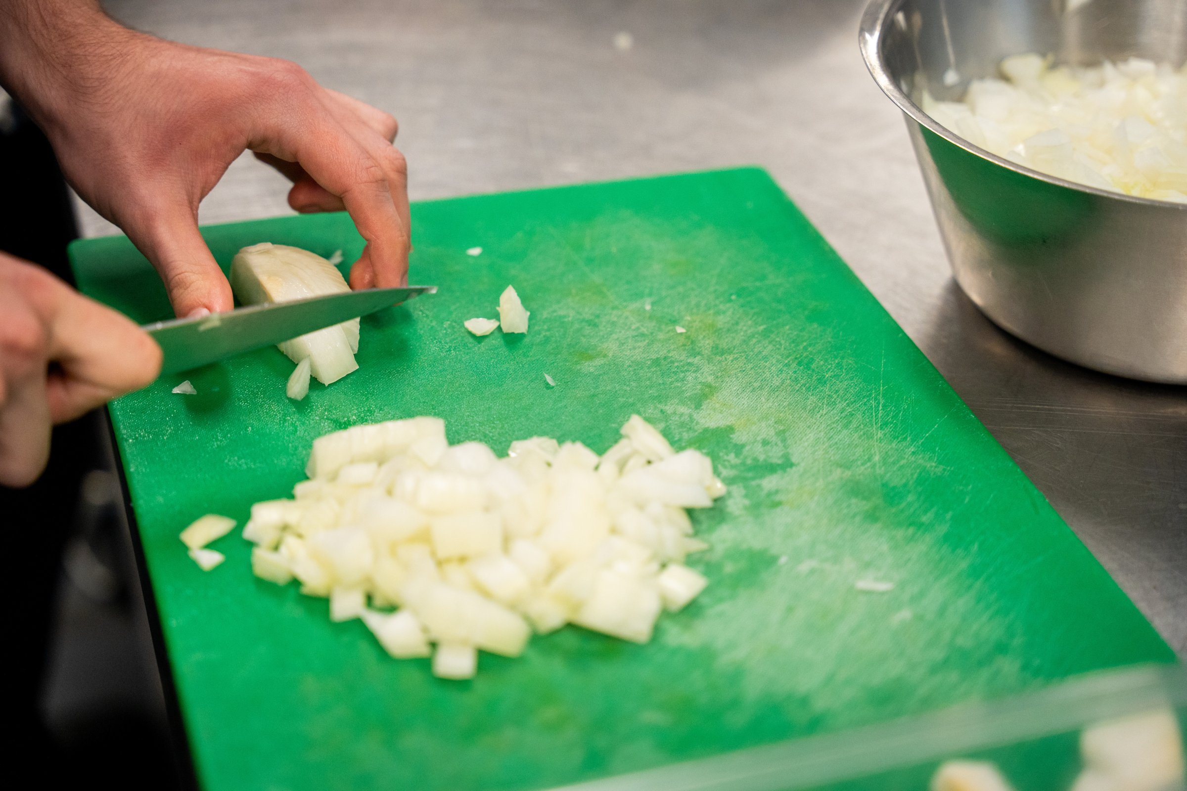 A hand chopping an onion on a chopping board