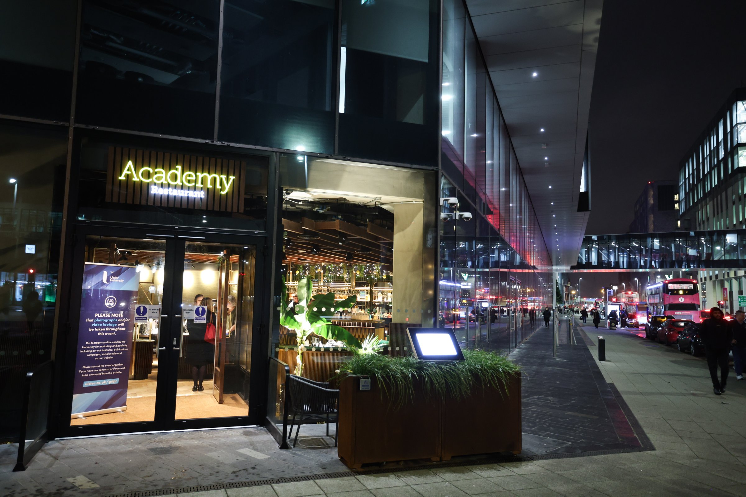Exterior view of Academy Restaurant at night in a modern city-centre location.