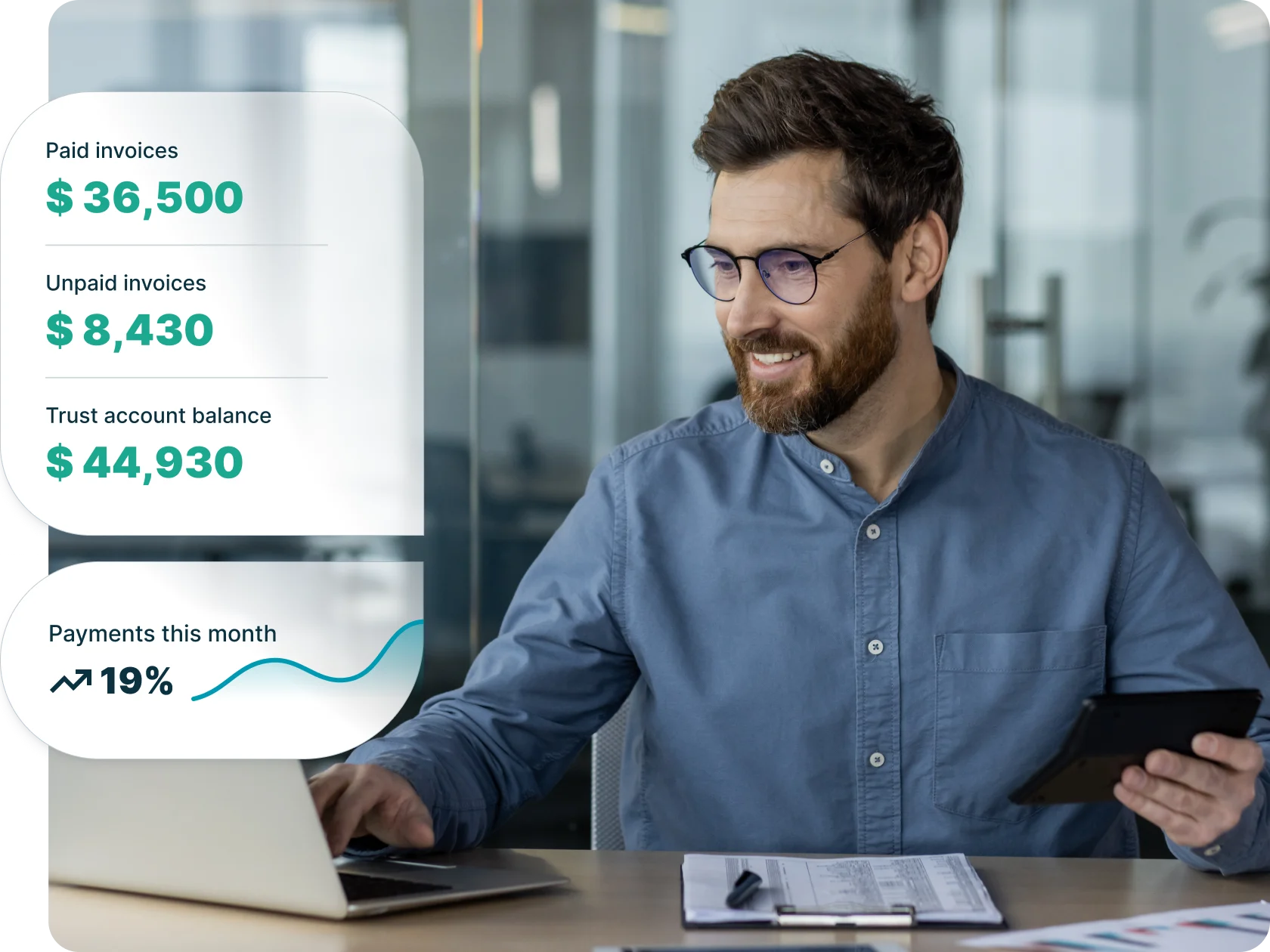 Man using laptop and tablet in office reviewing financial dashboard showing paid and unpaid invoices, trust balance, and monthly payments—illustrating billing software for professional services.