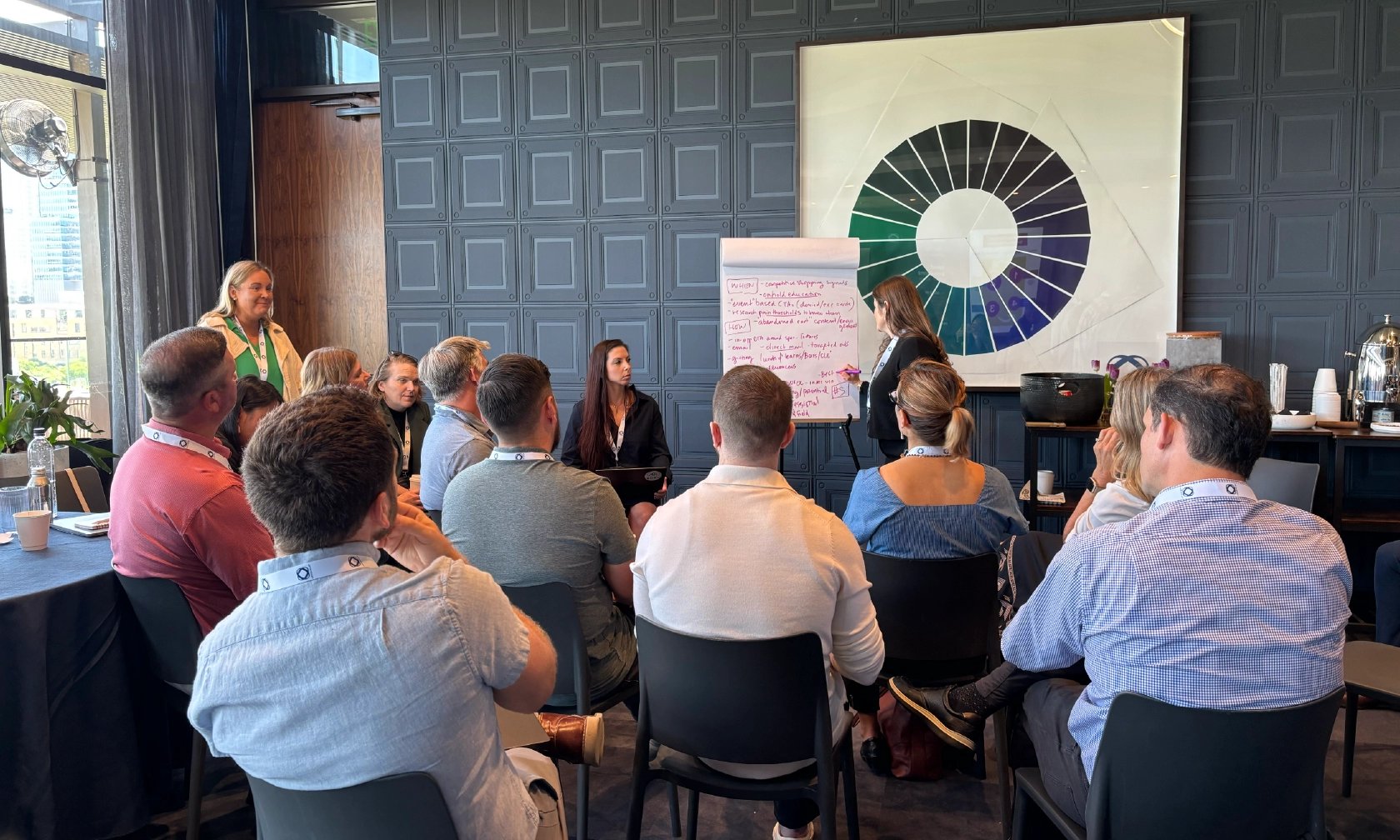 A group of employees seated in front of a speaker taking notes