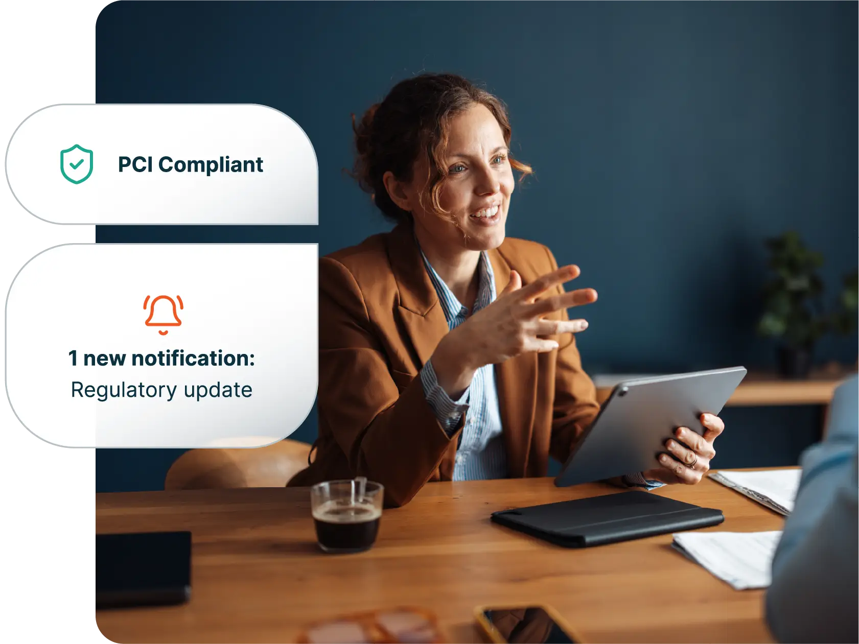 Smiling professional talking with a client at a desk, with floating cards reading “PCI Compliant” and “1 new notification: Regulatory update”