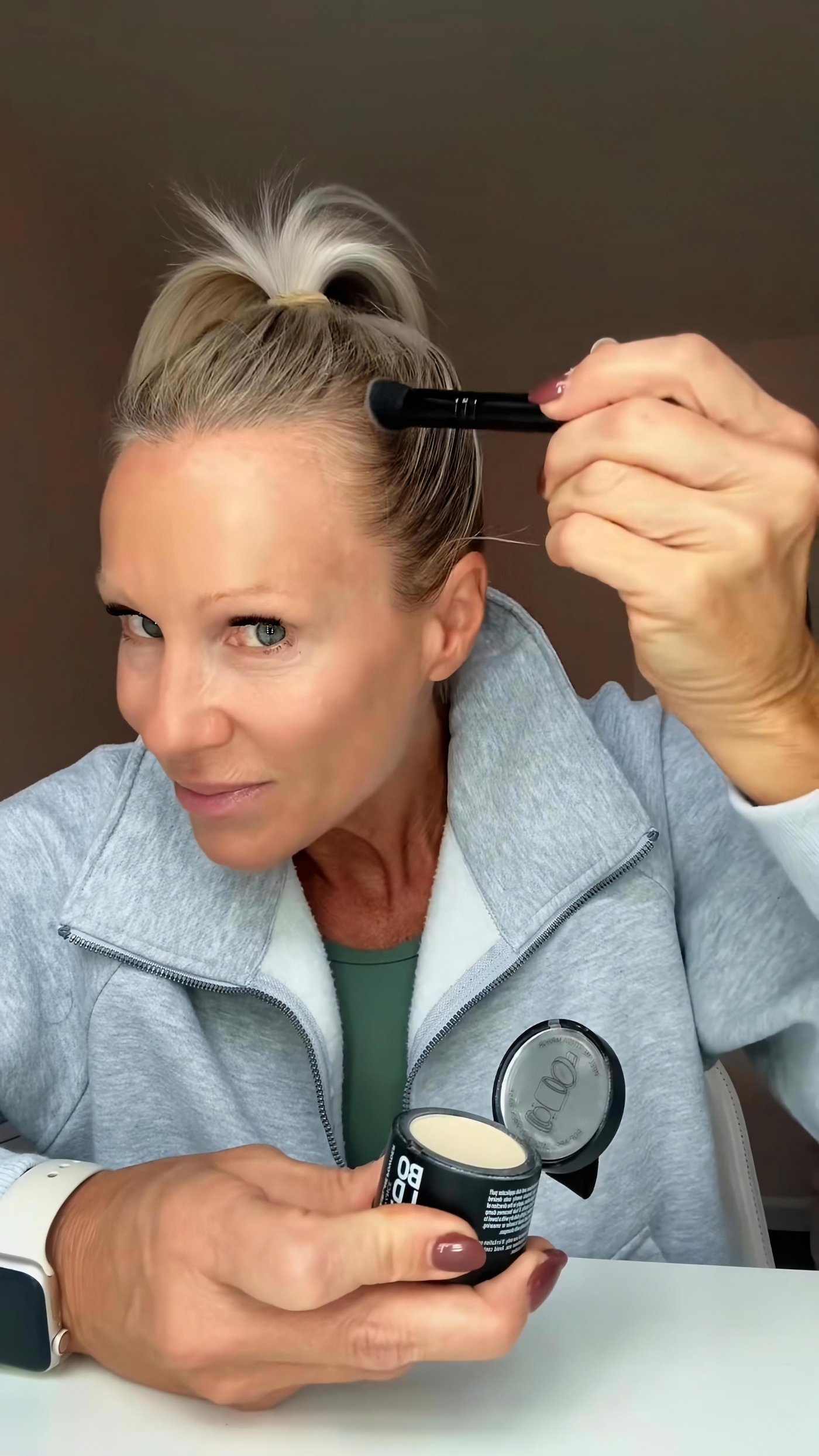 Applying Boldify Hairline Powder with a brush along visible gray roots at the hairline