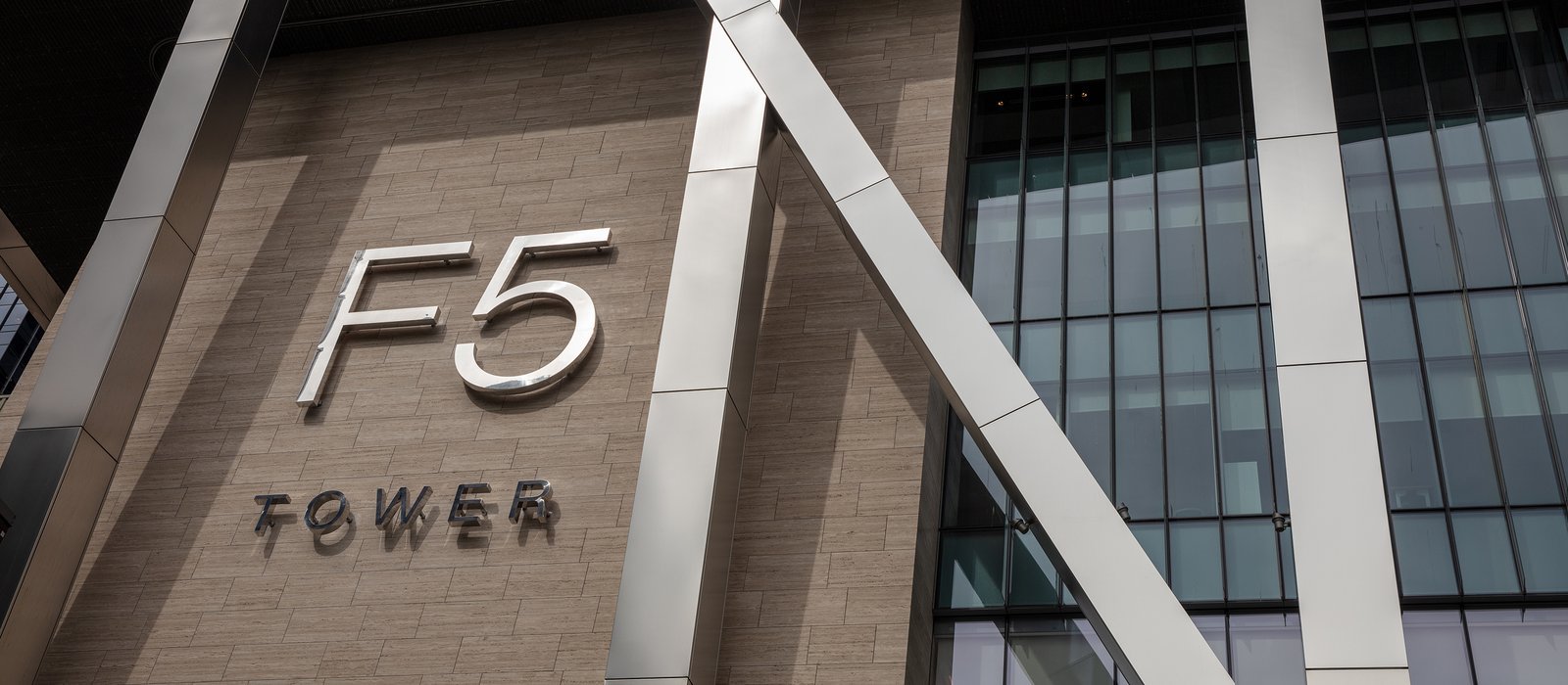 The F5 Tower sign in large metal letters on the stone and glass facade of F5’s headquarters building in Seattle
