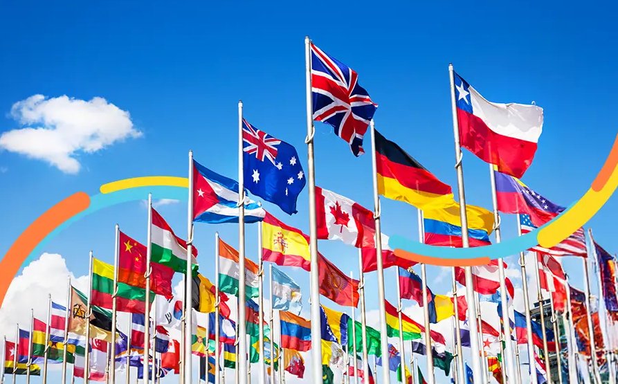 Banderas de países que comercializan internacionalmente, ondeando en mástiles al aire libre bajo un cielo azul.