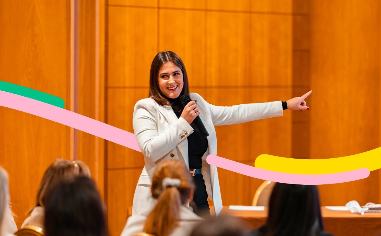 Persona en auditorio, presenta un evento temático para colaboradores de un negocio. 