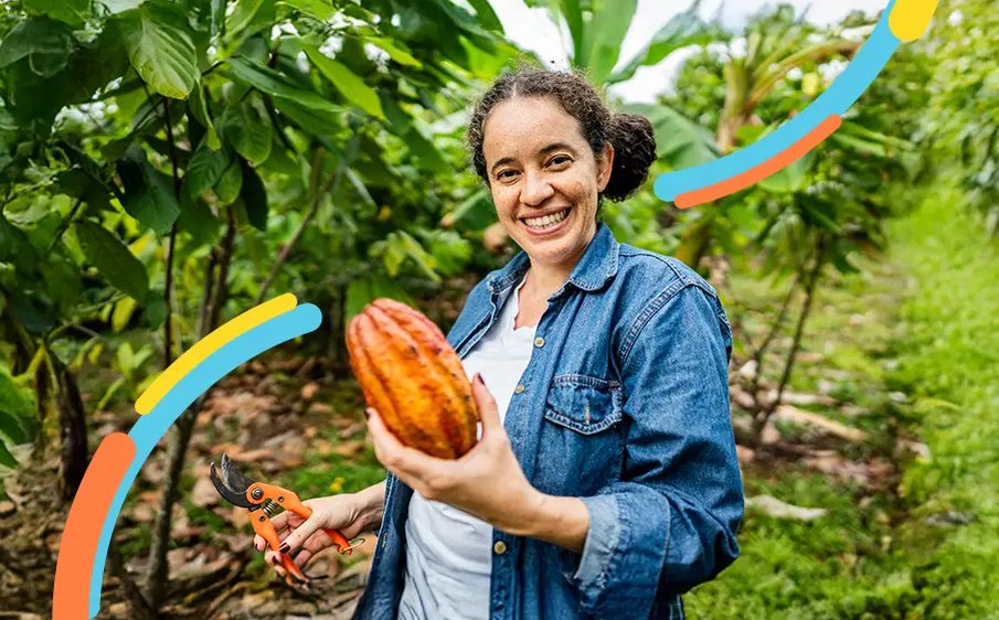 Mujer sostiene una mazorca de cacao y unas tijeras de poda en un cultivo para empezar a exportar con la guía de comercio internacional.