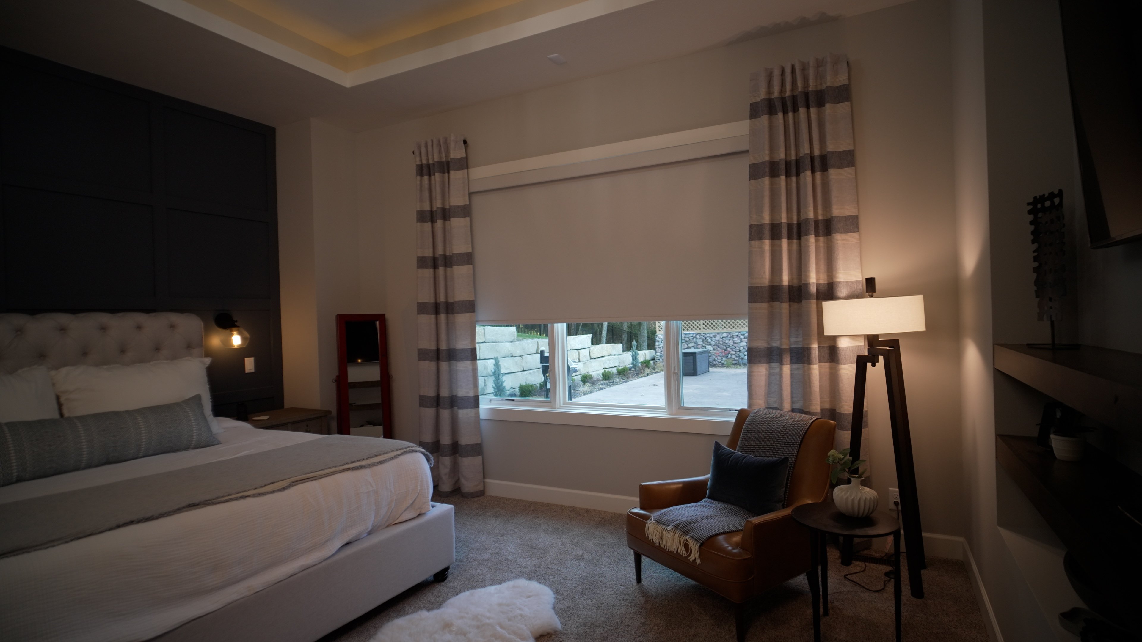 Blackout roller shade paired with drapery panels to create a dark cozy bedroom