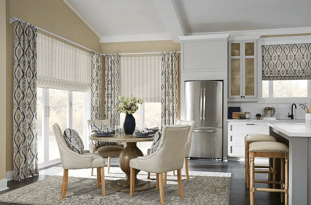 Patterned drapery layered with neutral patterned roman shades