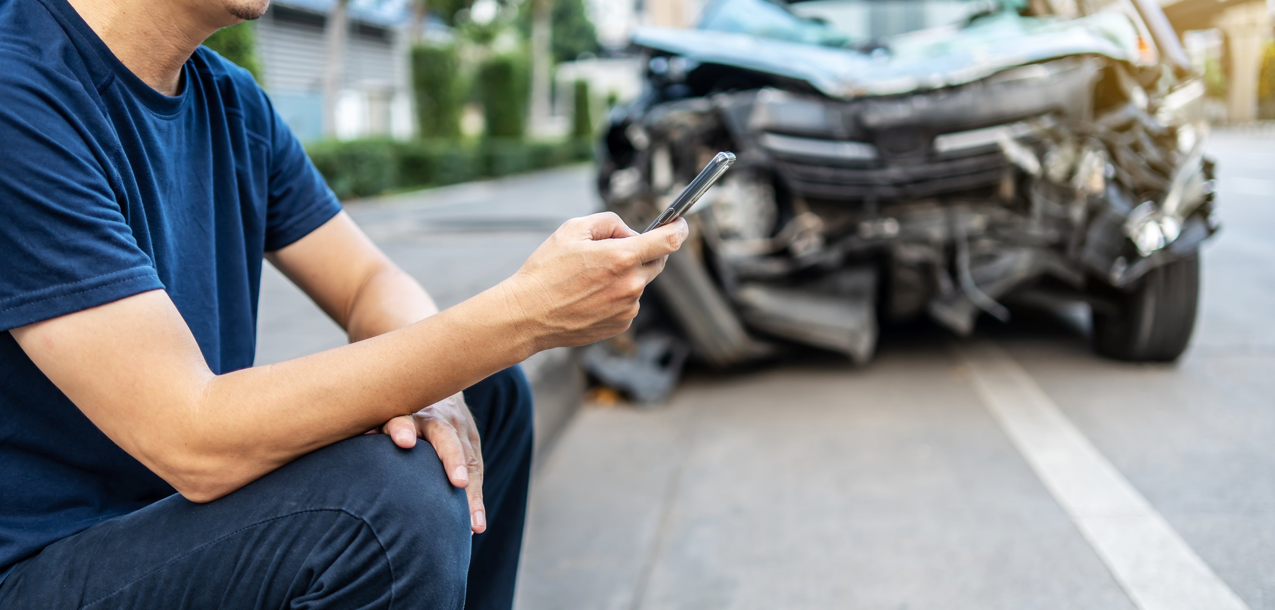 Man calling with phone to his insurance agent after traffic accident