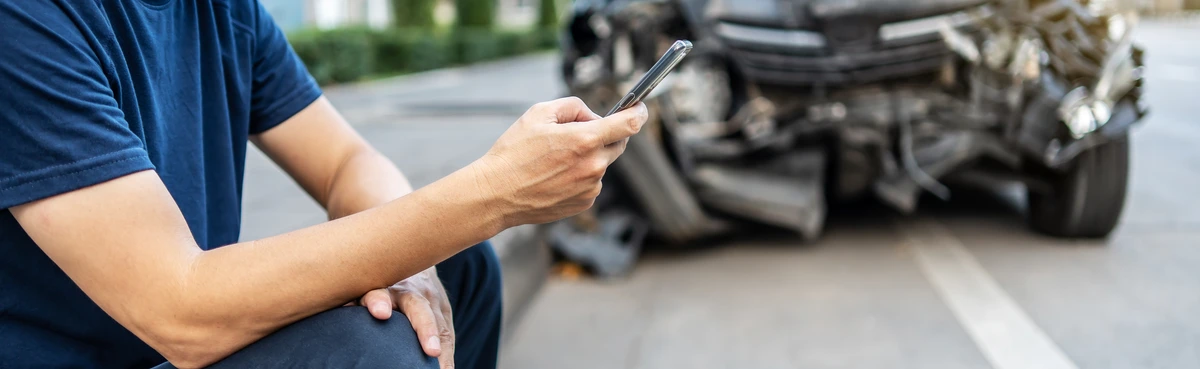 Man calling with phone to his insurance agent after traffic accident