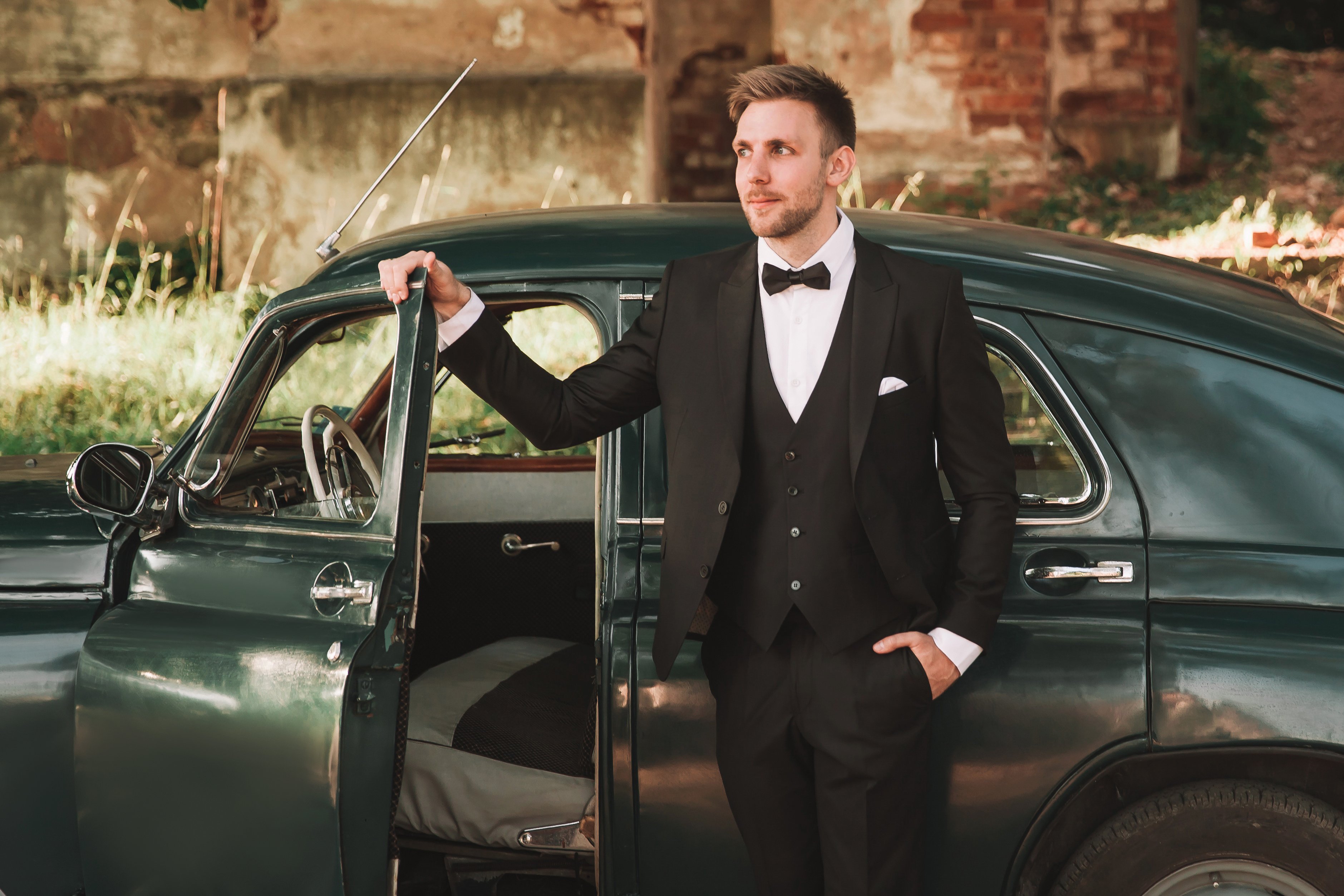 Man in tuxedo dressed as James Bond standing in front of car