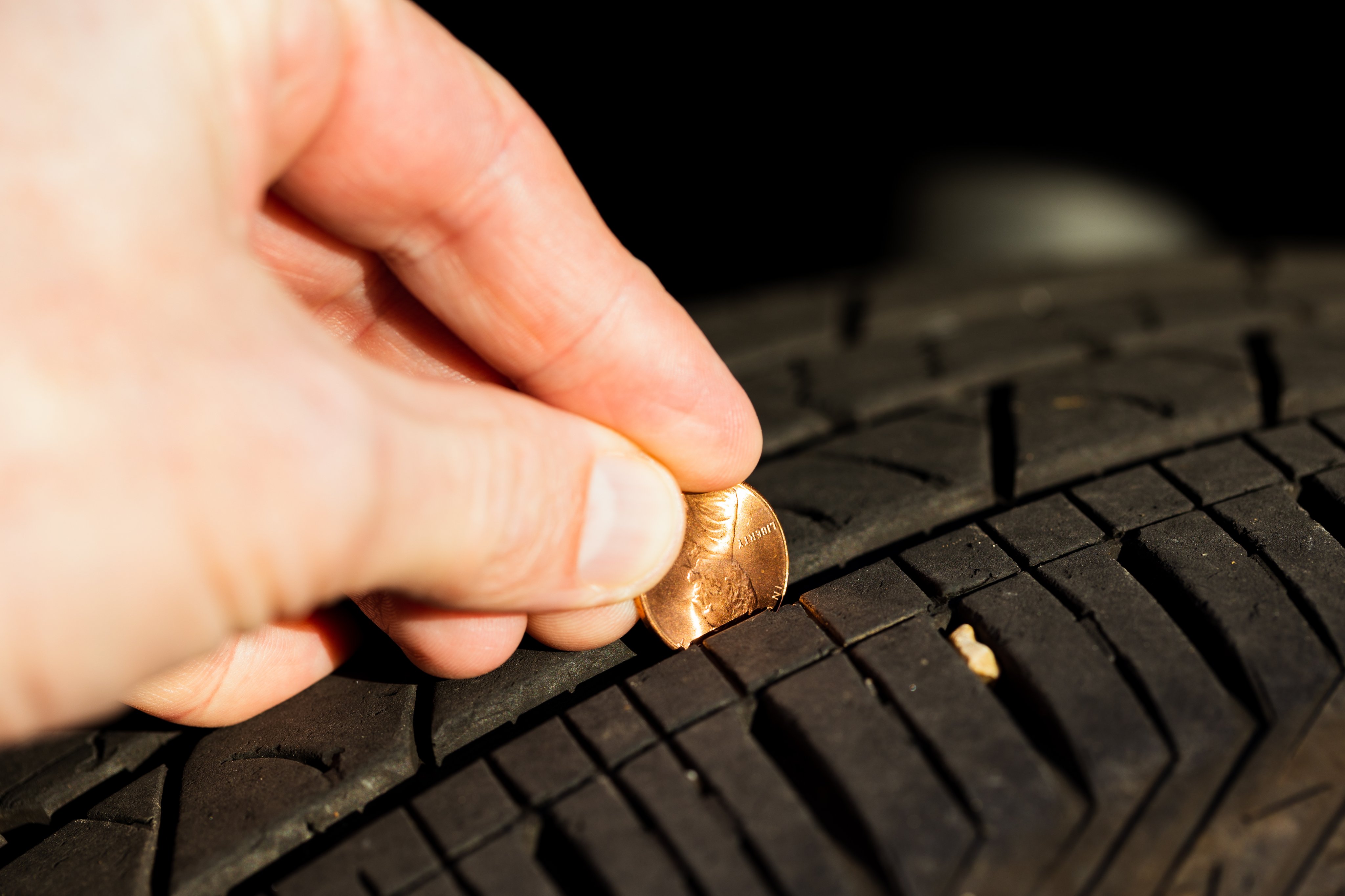 Checking tread depth on a tire by using a penny.