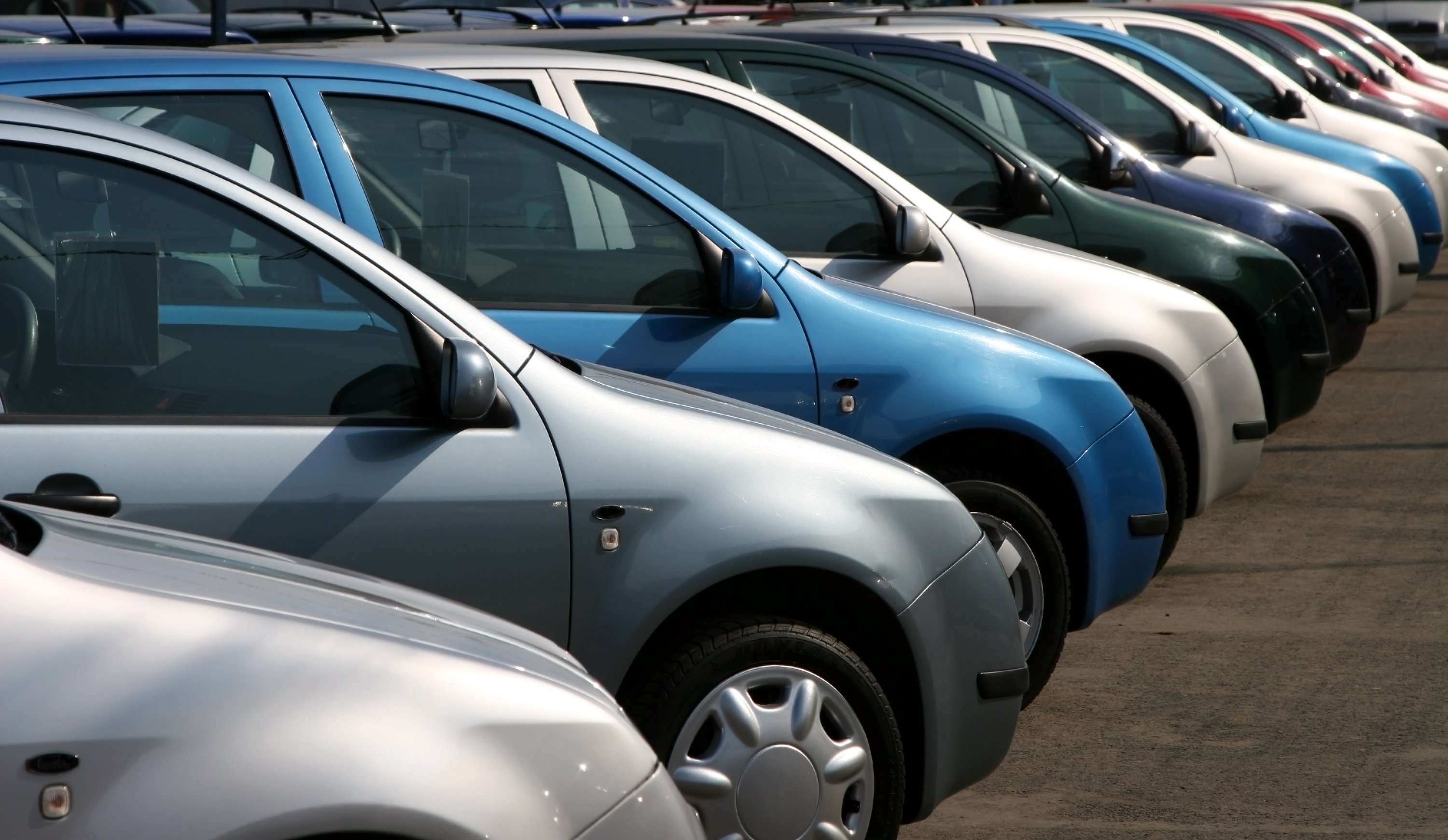 Row of parked cars lined up neatly in a parking lot.