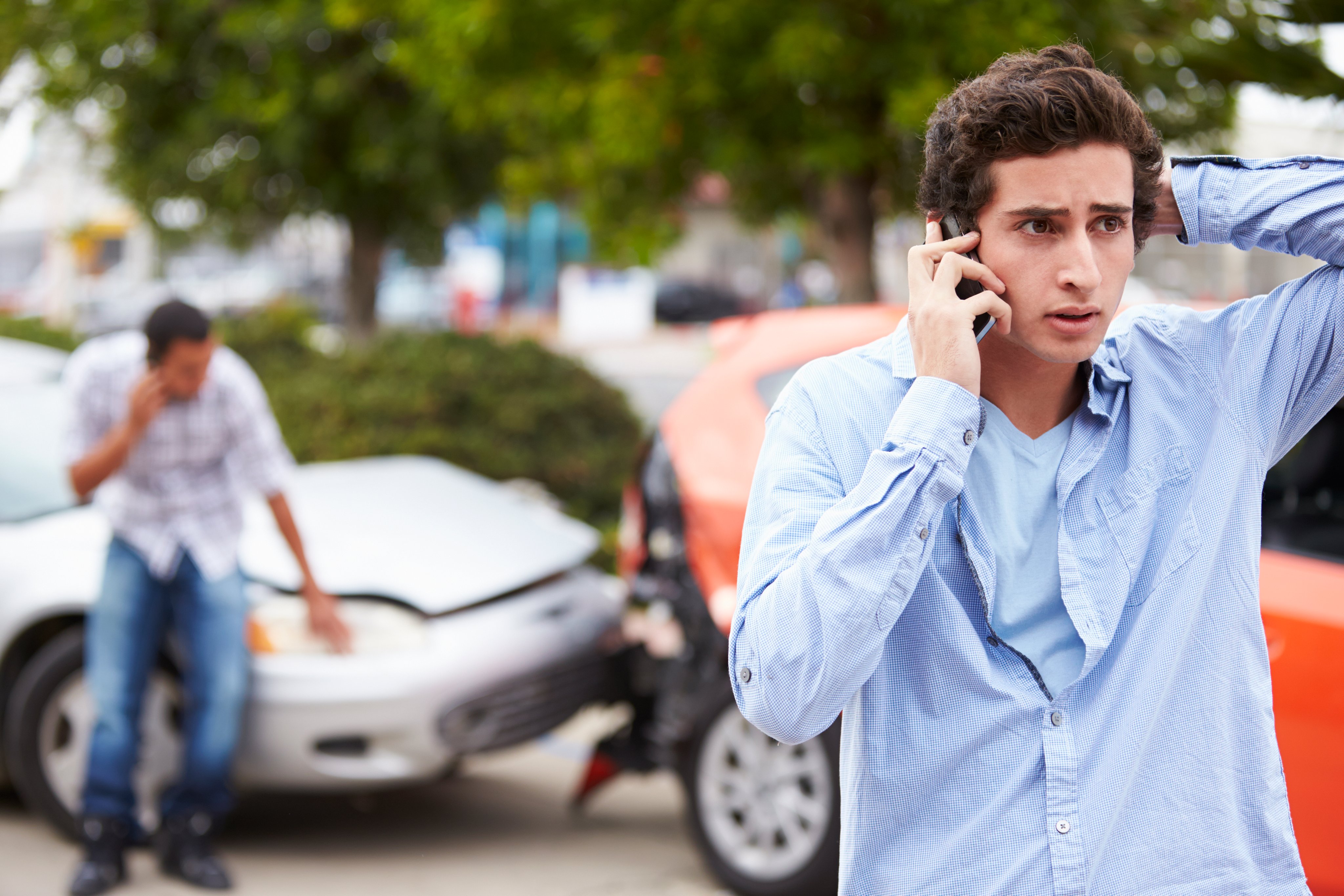 Teenage Driver Making Phone Call After Traffic Accident With Crash In Background
