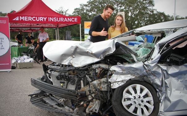 Father and daughter looking at a wrecked car