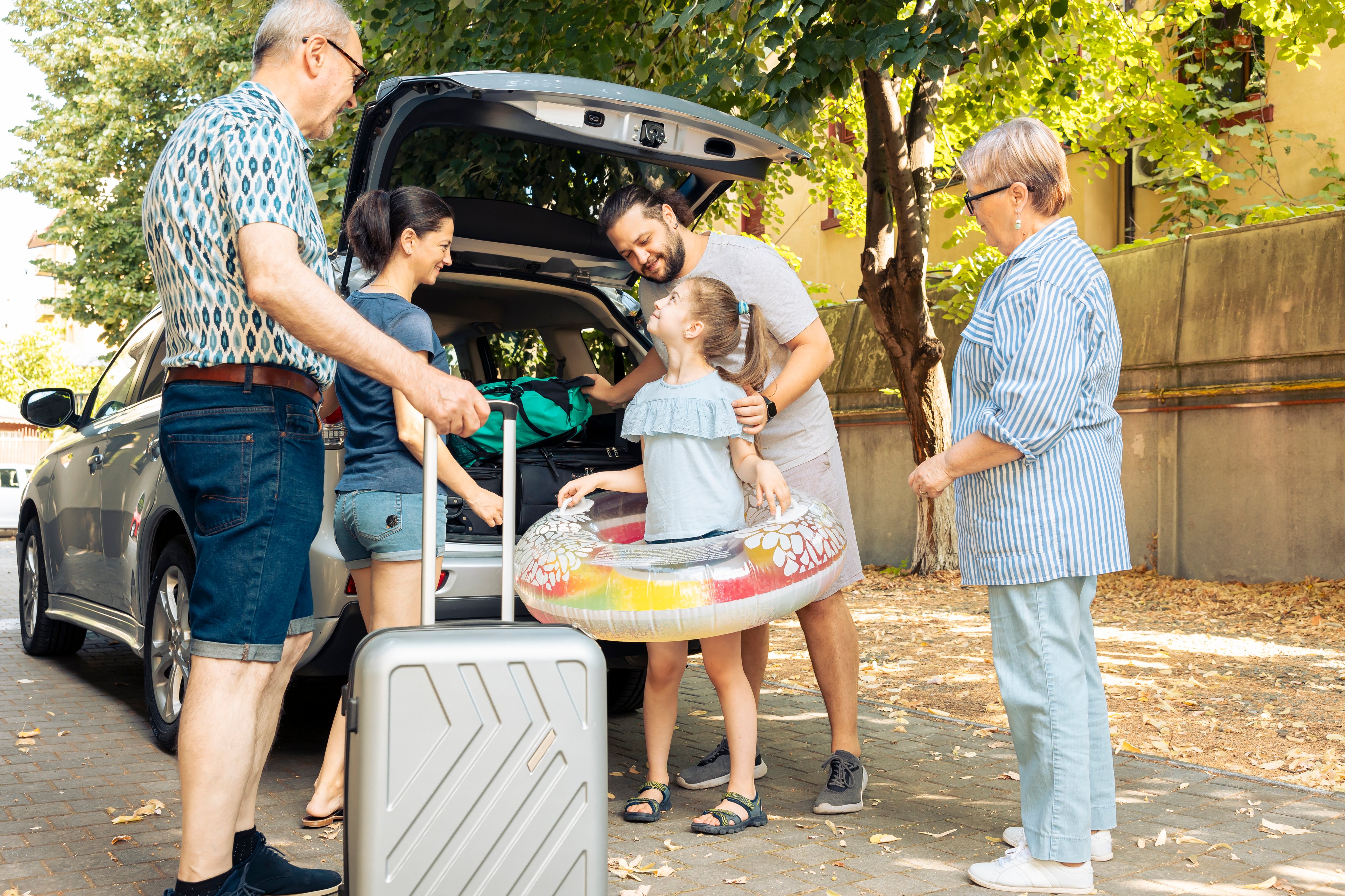 Family packing luggage into an SUV before leaving on a vacation road trip.