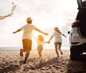 Family running together and flying kite on a beach