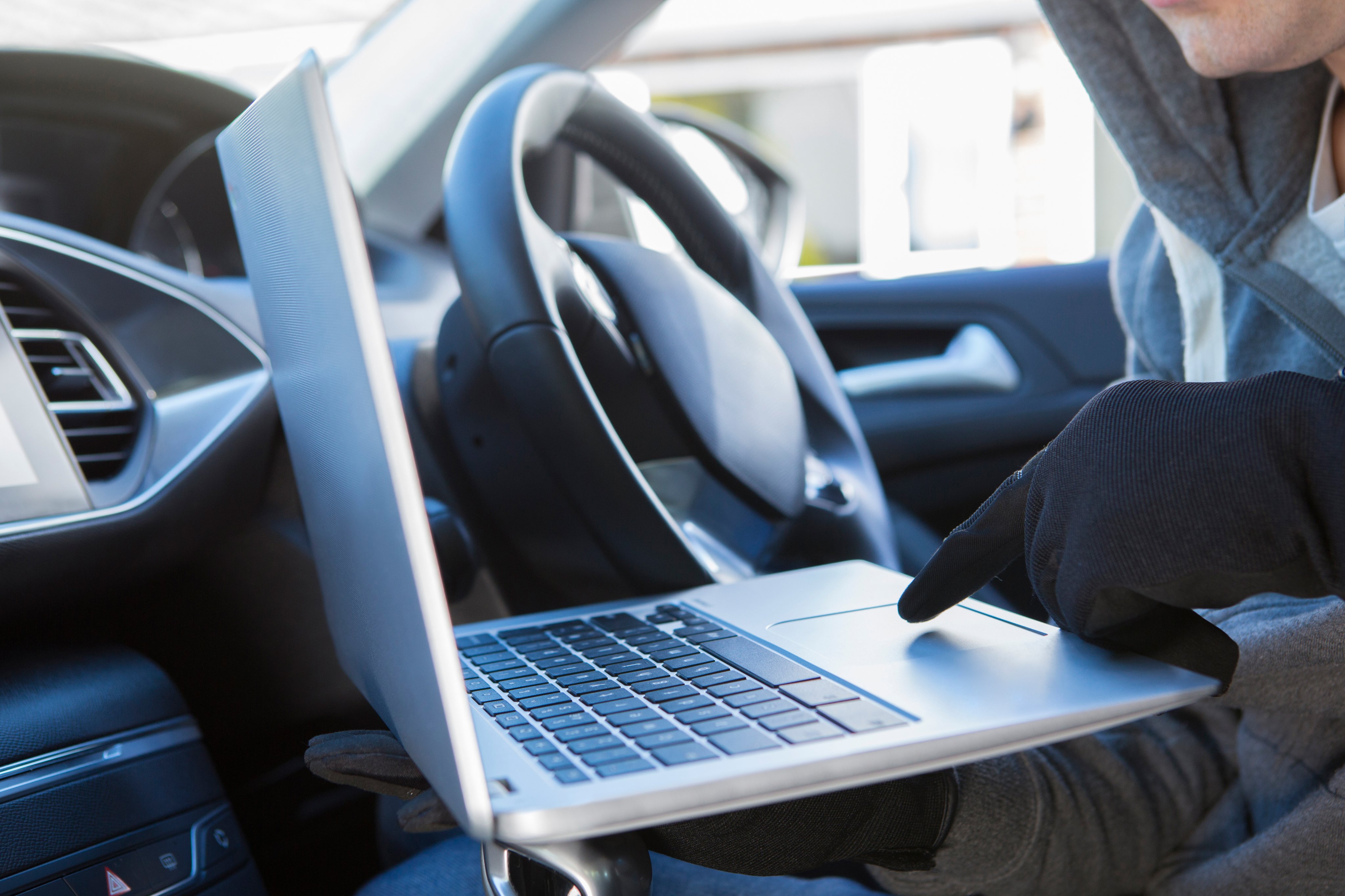 Burglar using a laptop to hack into a vehicle