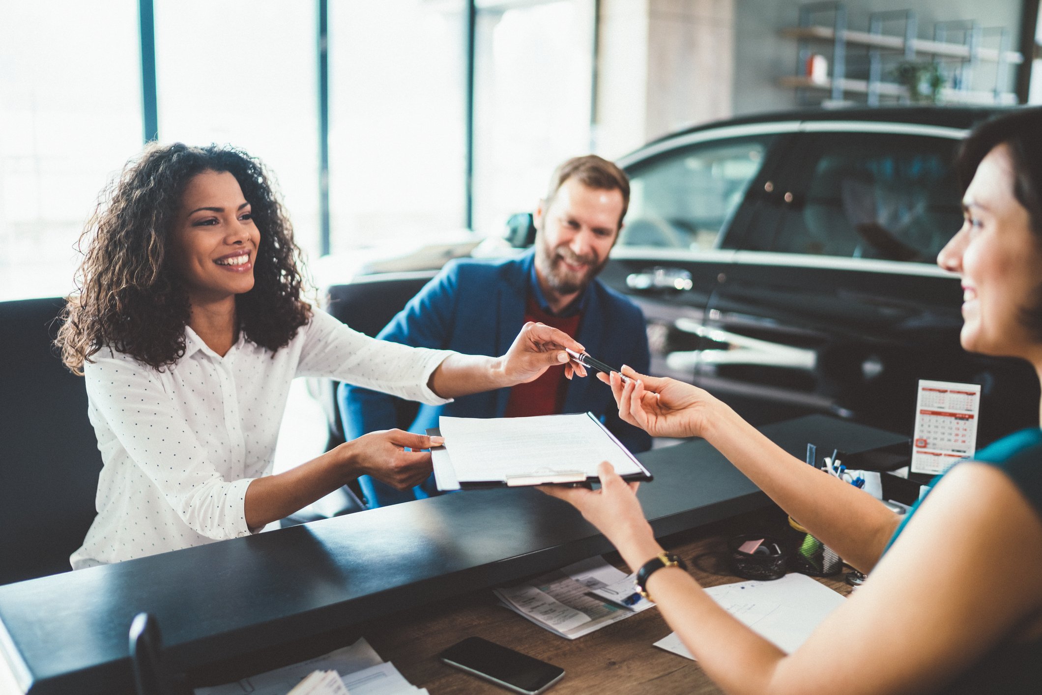 Couple in the showroom signing paperwork and buying new car