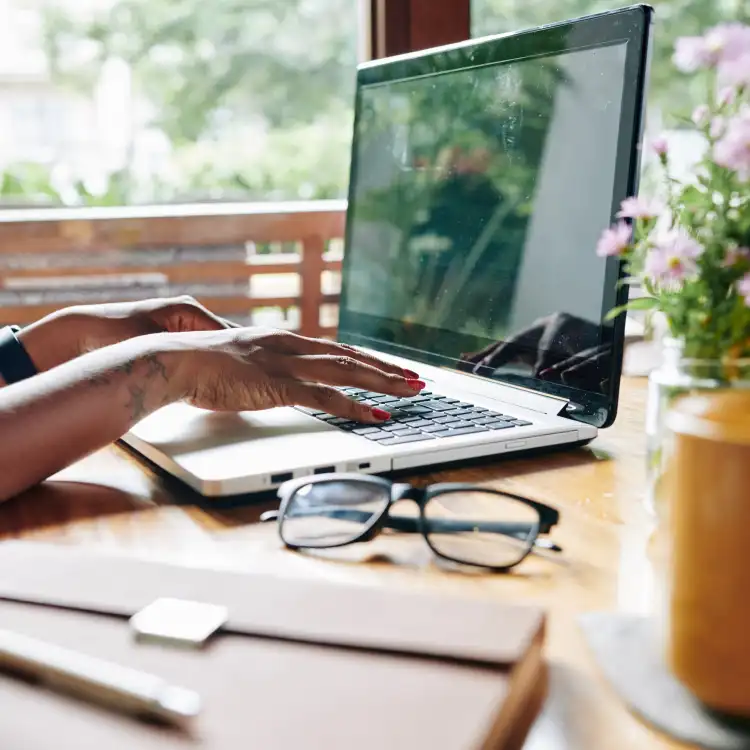 Close-up of a woman sitting at the table and working on laptop at home