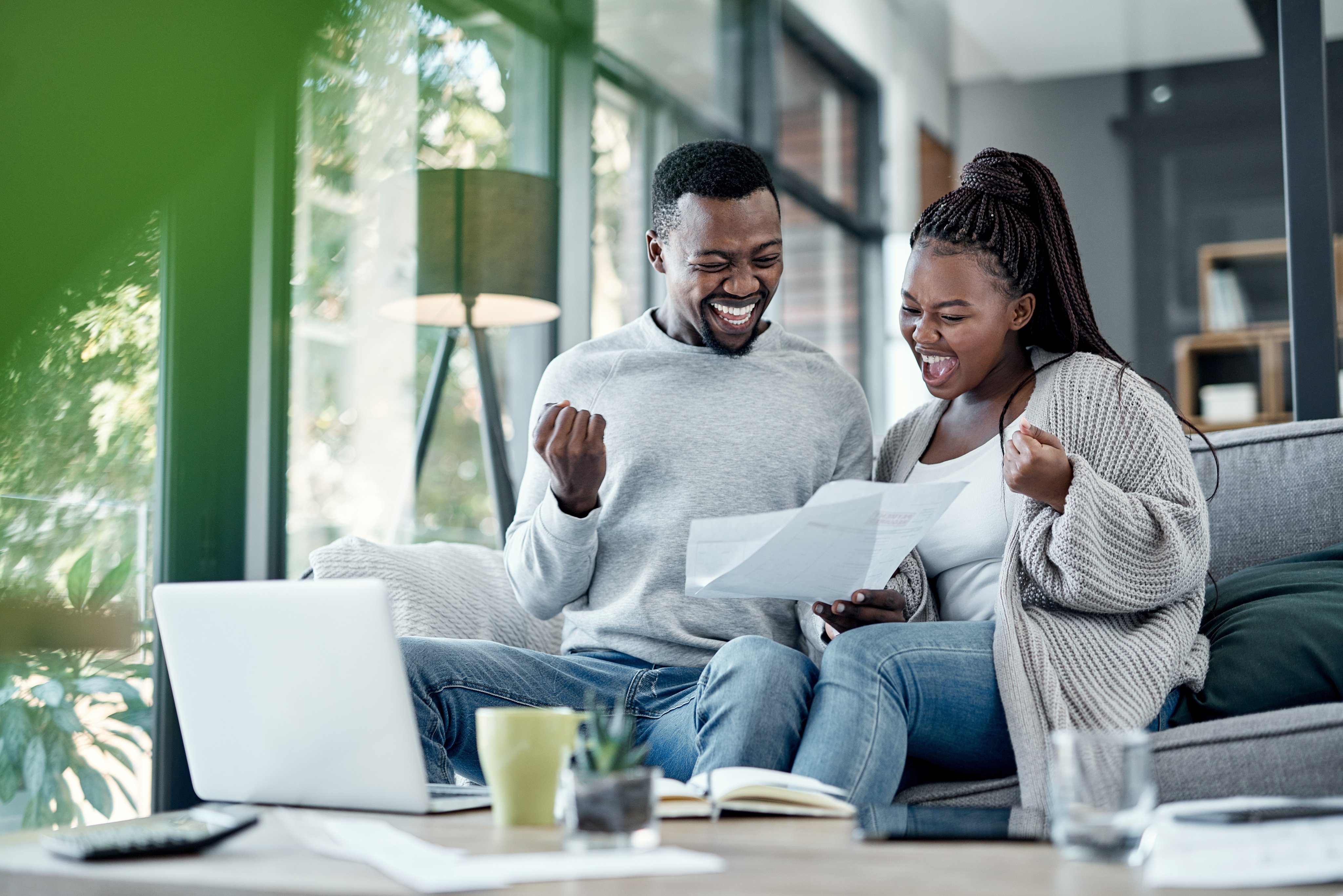 Shot of a young couple celebrating while going through paperwork at home