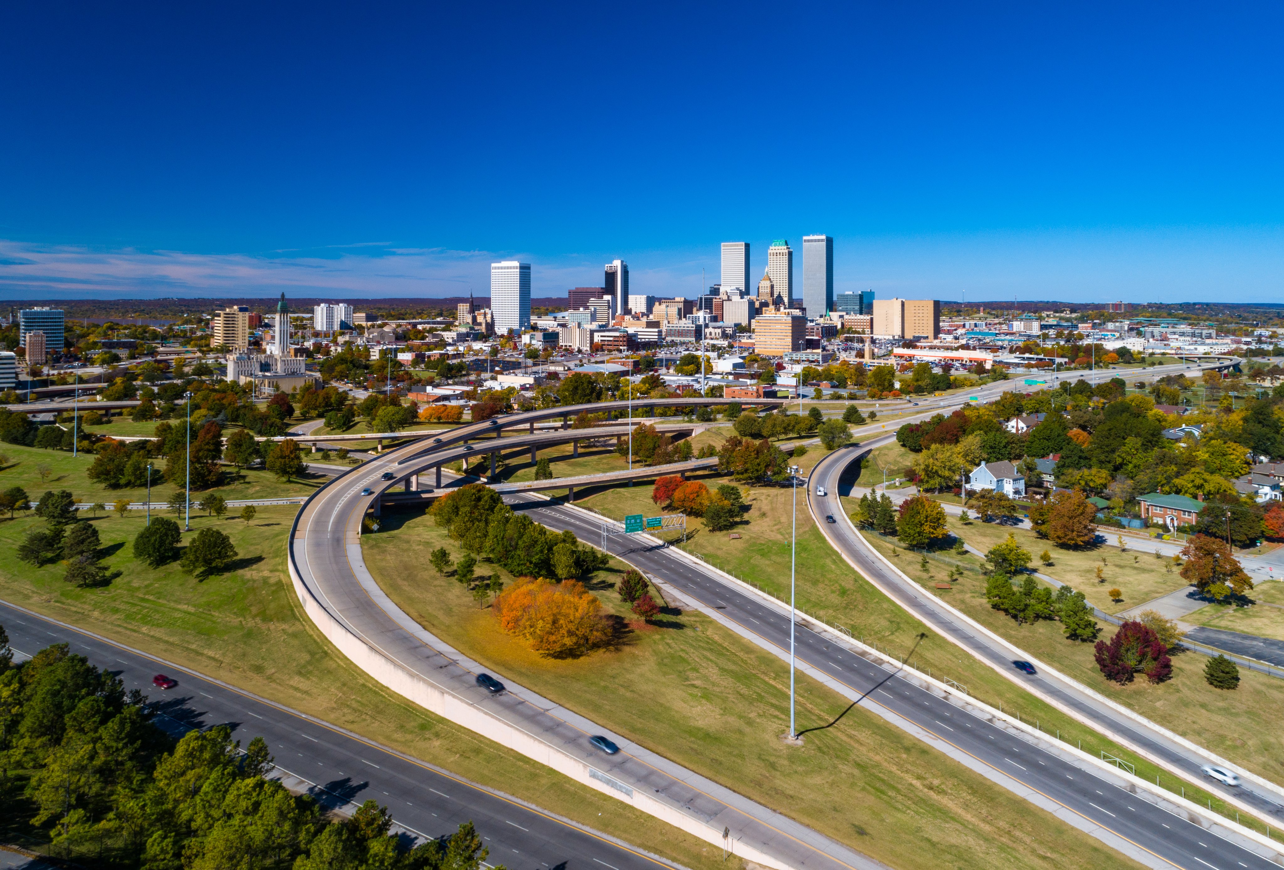 
Aerial view of downtown Tulsa skyline with grass, trees, and freeways in the foreground