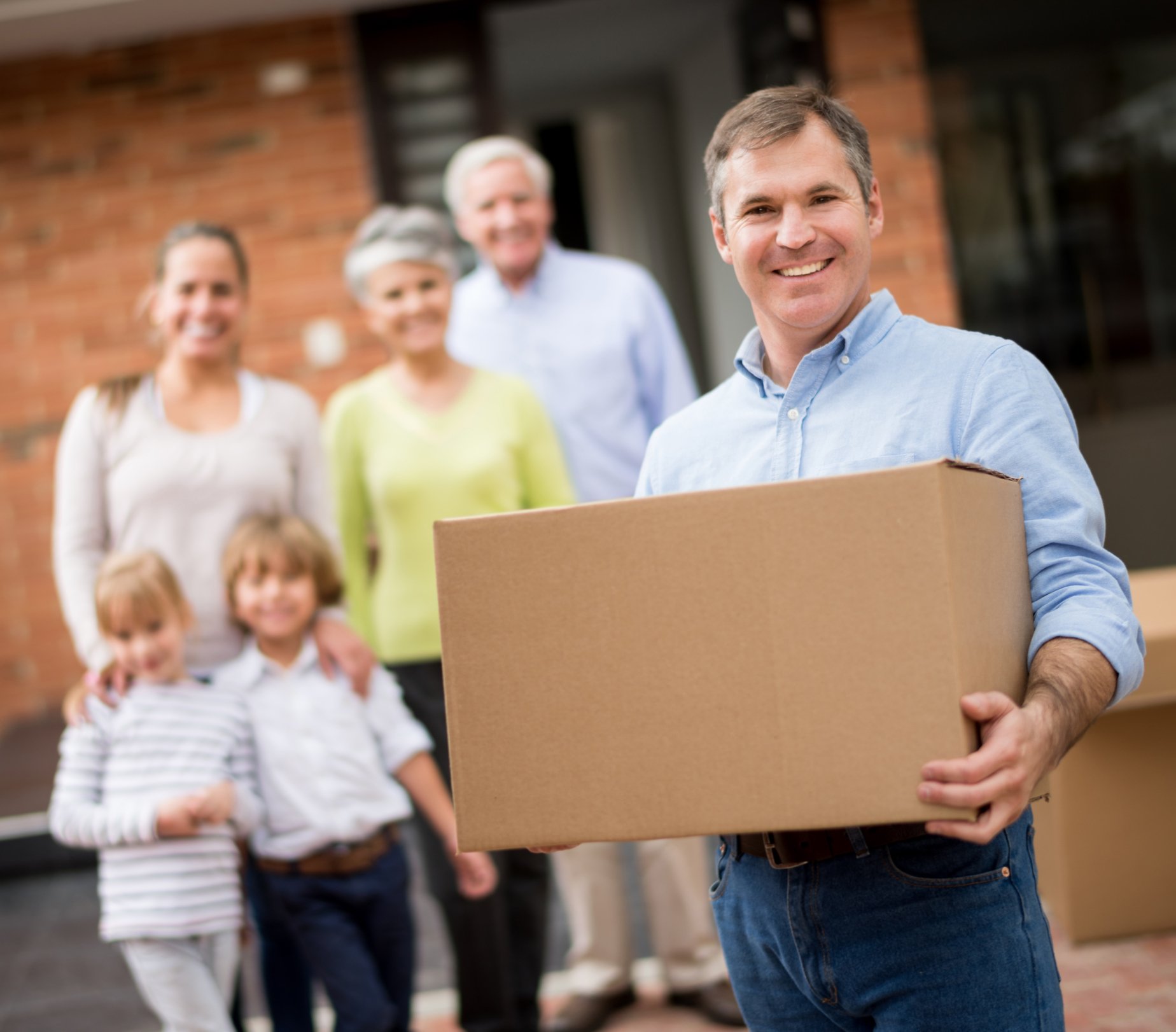Man moving into a house with his family and holding a cardboard box