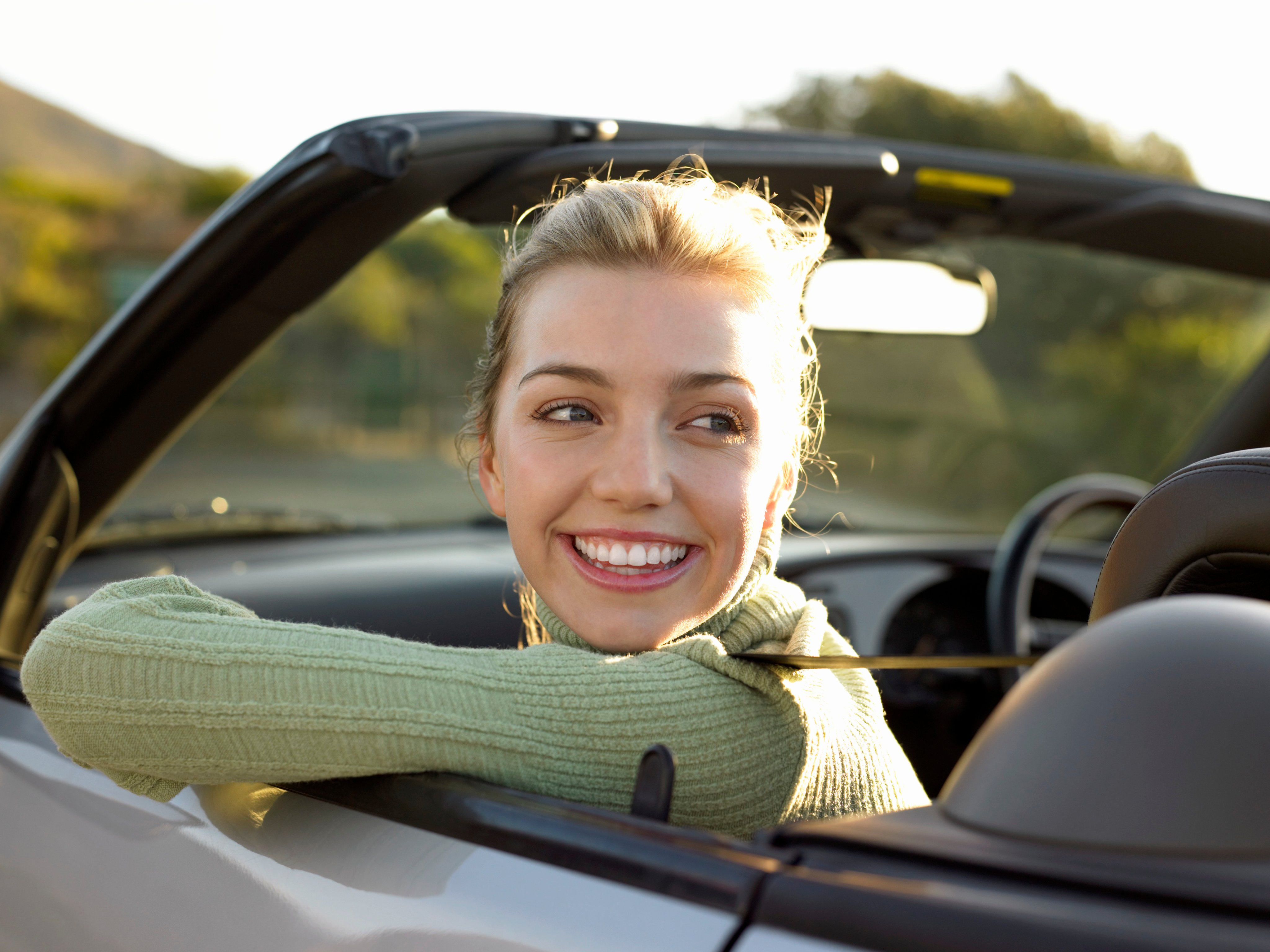 Woman smiling in passenger seat of convertible car