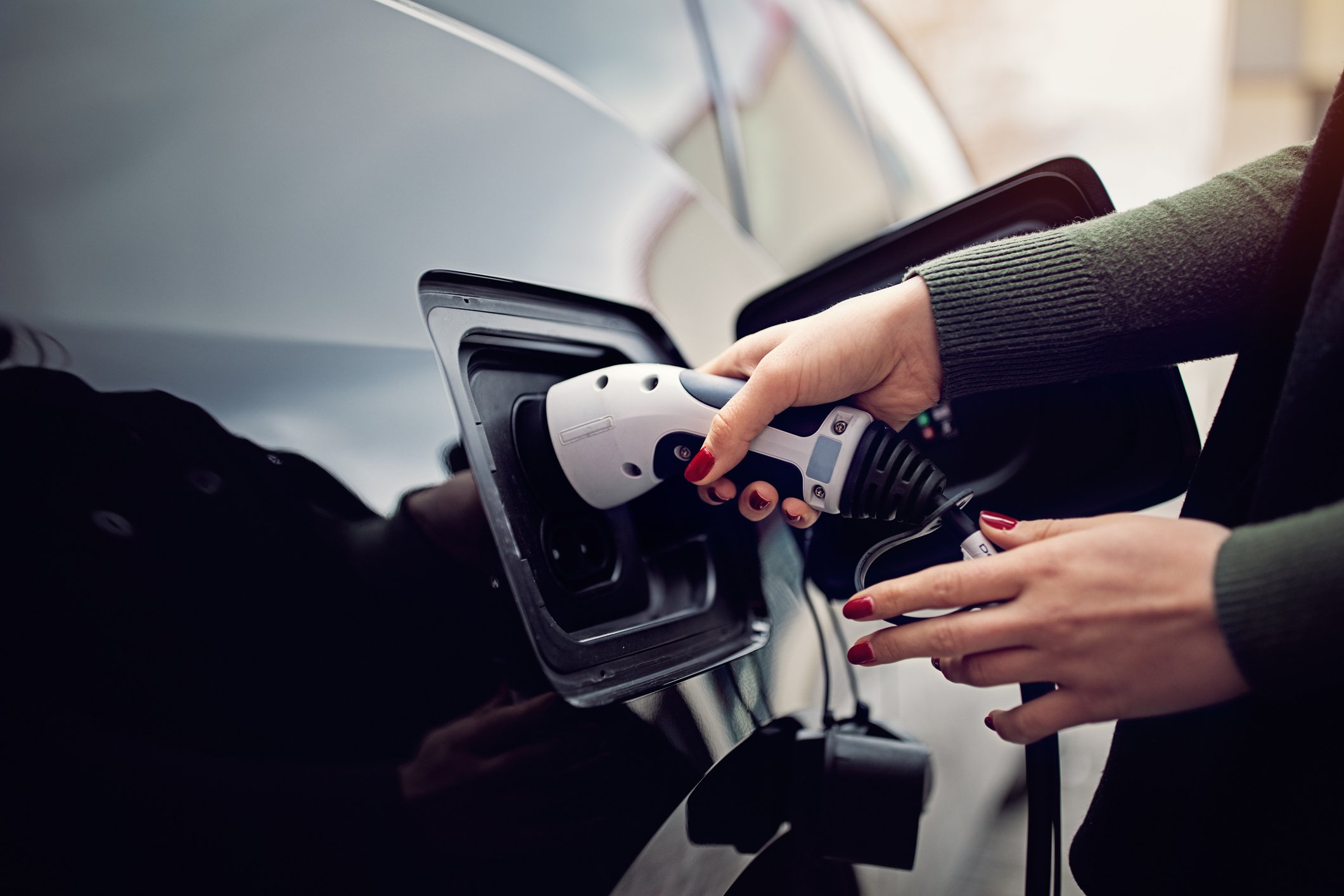 Woman plugging charging cable into a electric car